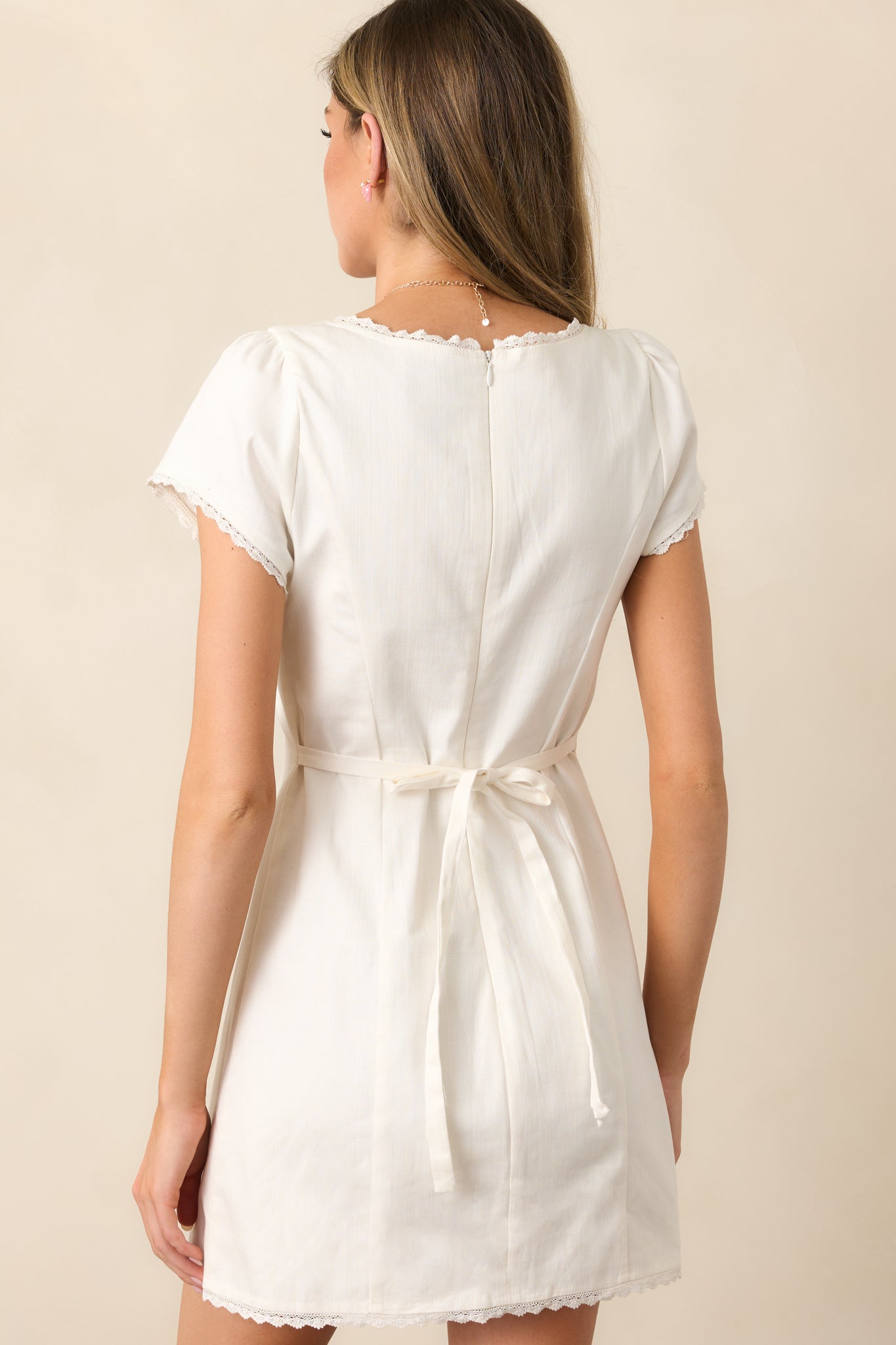 A back view of the white mini dress, showcasing the clean lines and flowy silhouette