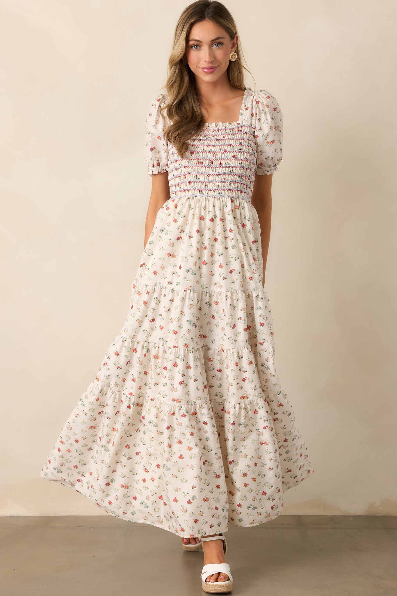 A delicate floral print is scattered across the ivory fabric, enhancing the dress’s timeless and feminine appeal.