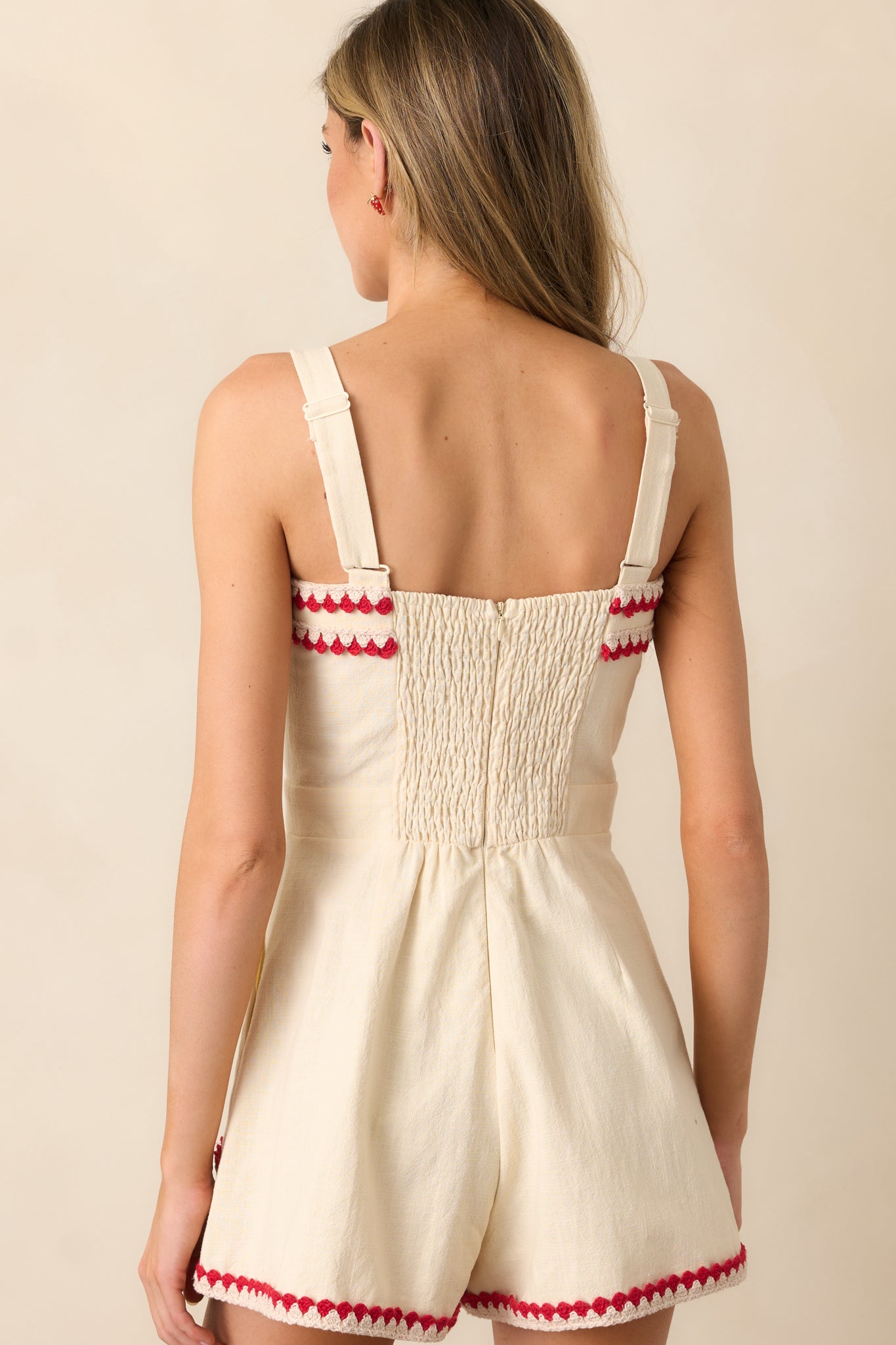 A view from behind, displaying the smocked back, adjustable straps, and the way the romper fits at the waist.