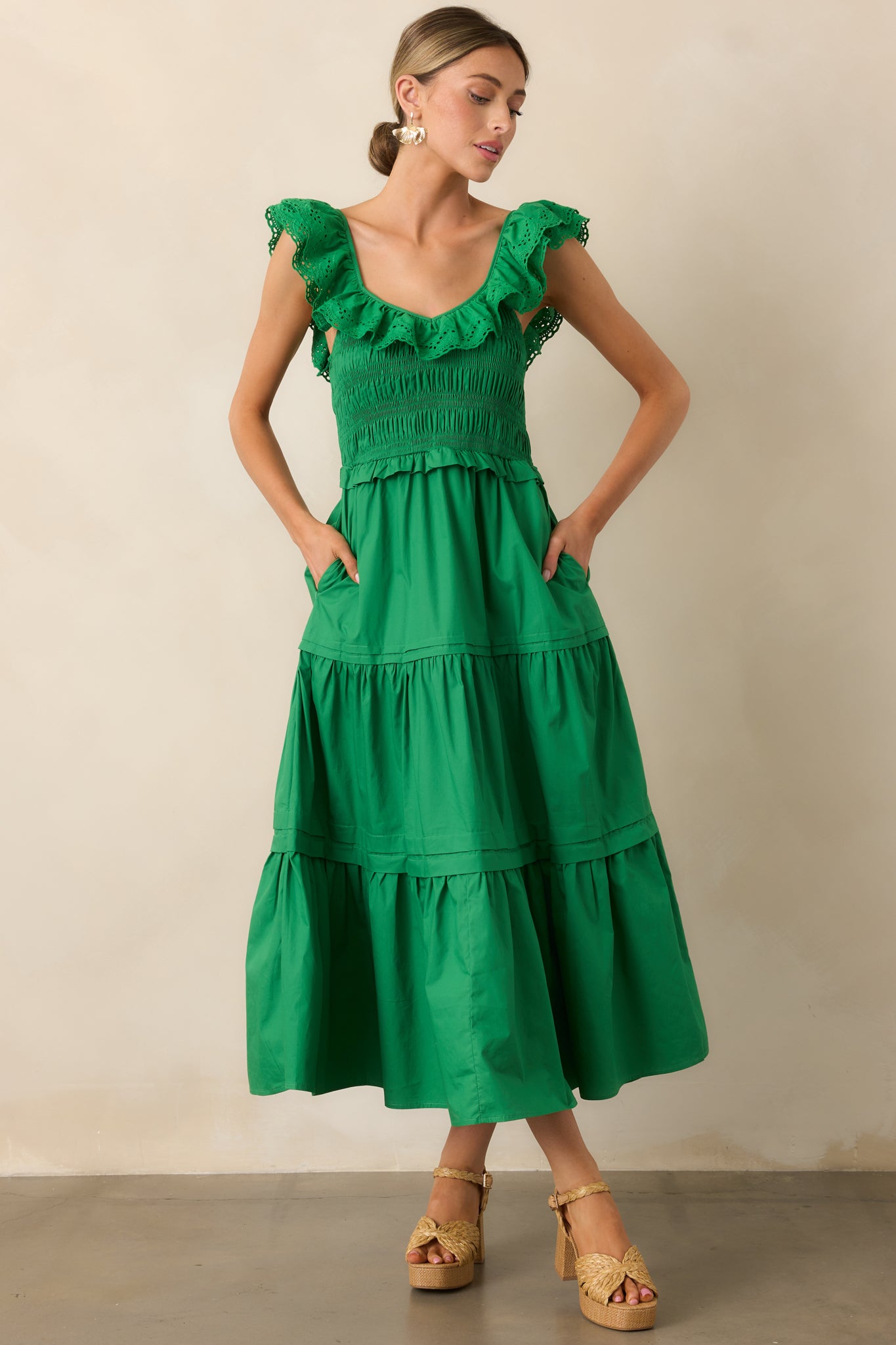 A flowy green maxi dress designed with a ruffled V-neckline, smocked bodice, and tiered skirt, complete with functional pockets for convenience.