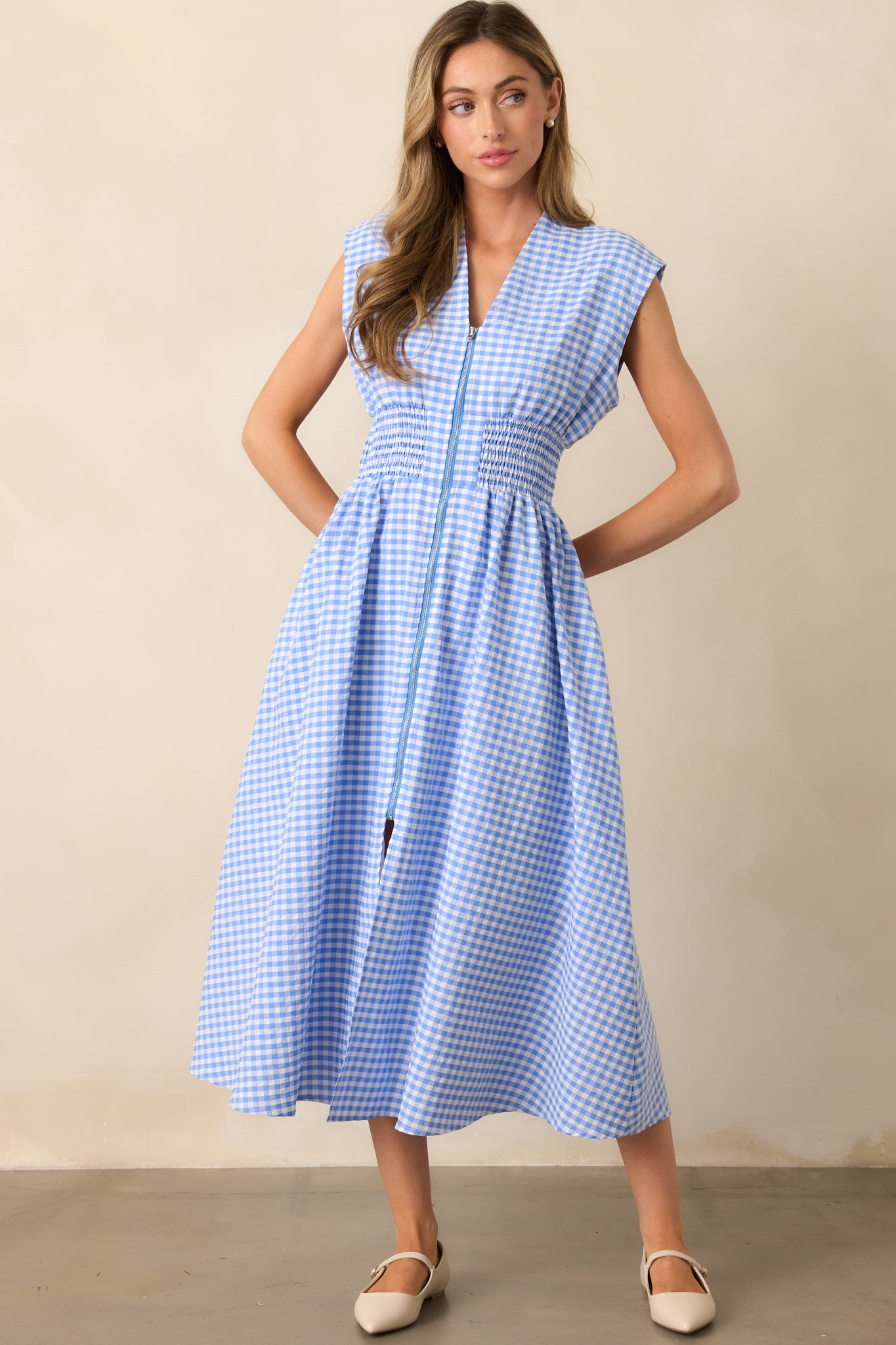  The structured padded shoulders and capped sleeves add definition to the gingham midi dress, complementing the fitted smocked waist.