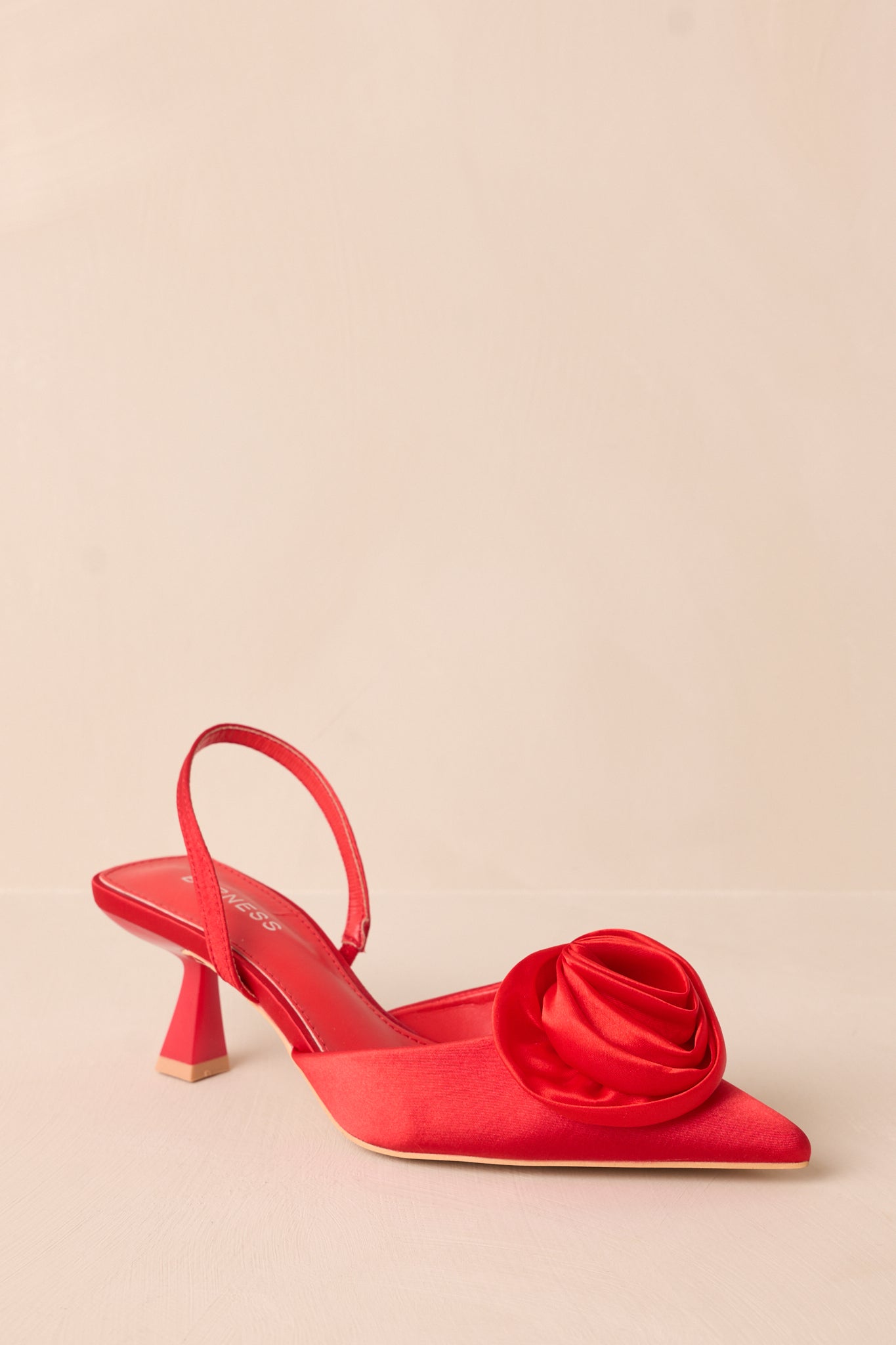 A detailed view of the rose toe accent, focusing on its texture and vibrant color against the red shoe.