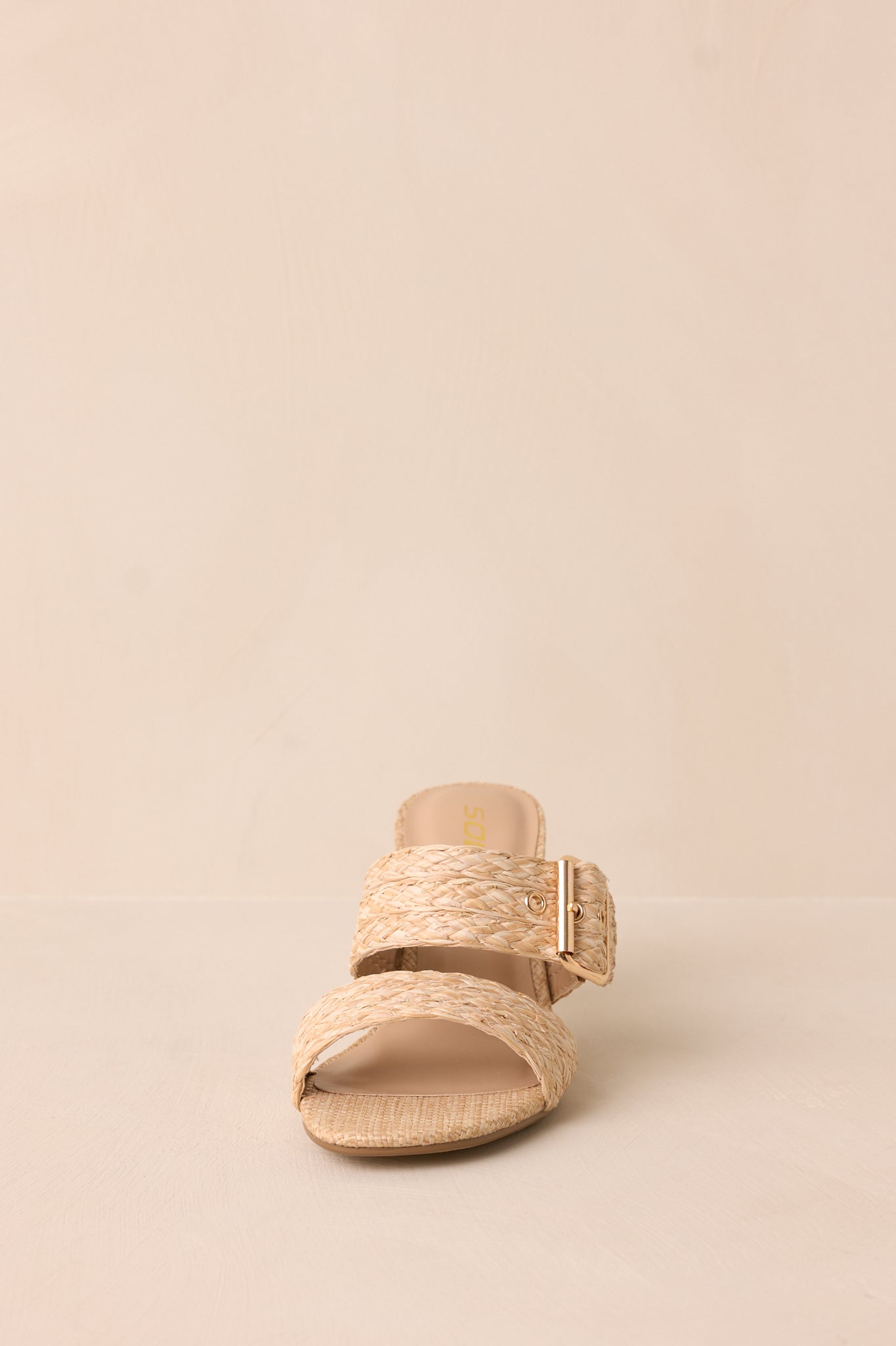 A front-facing view of the heels, emphasizing the rounded toe and woven straps