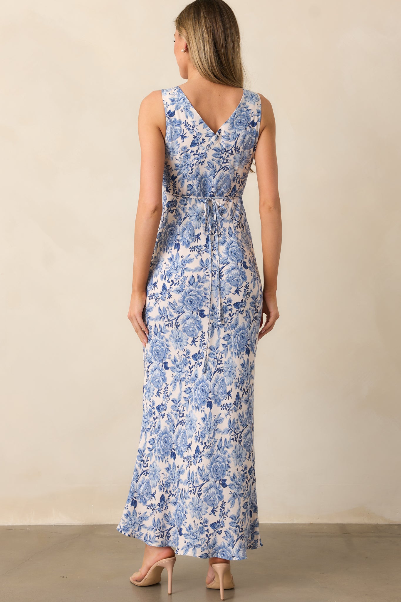 The back of the dress features a self-tie detail, fitted shape, and a flowing maxi-length skirt.