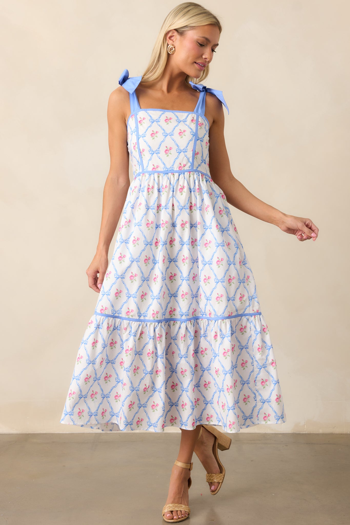 The blue dress showcases self-tie ribbon straps, a square neckline, and smocked back detailing. The dress also includes functional pockets for added convenience.