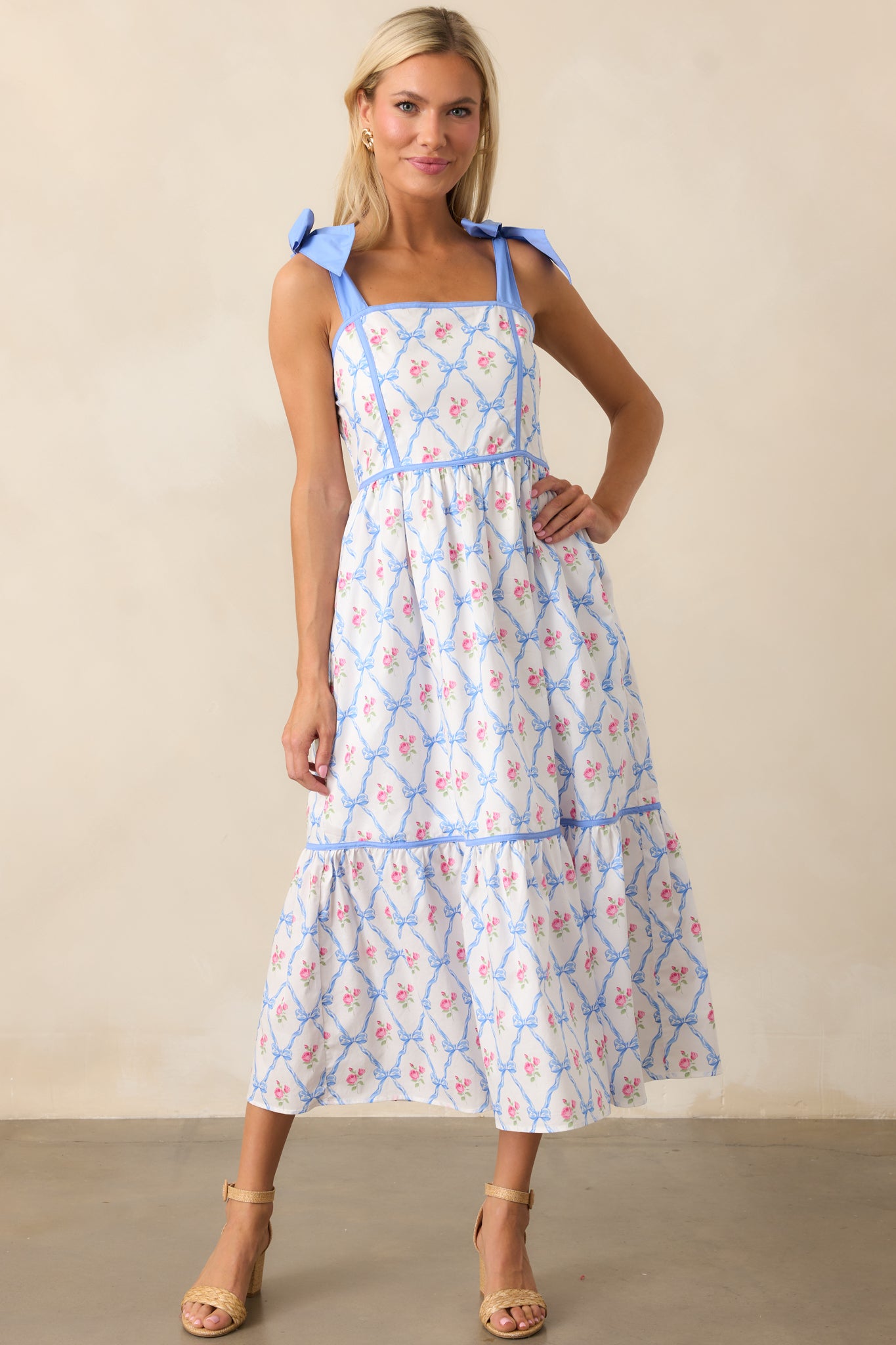 This blue dress features self-tie ribbon straps, a square neckline, and a smocked back. Functional pockets add a practical touch to the flowy silhouette.