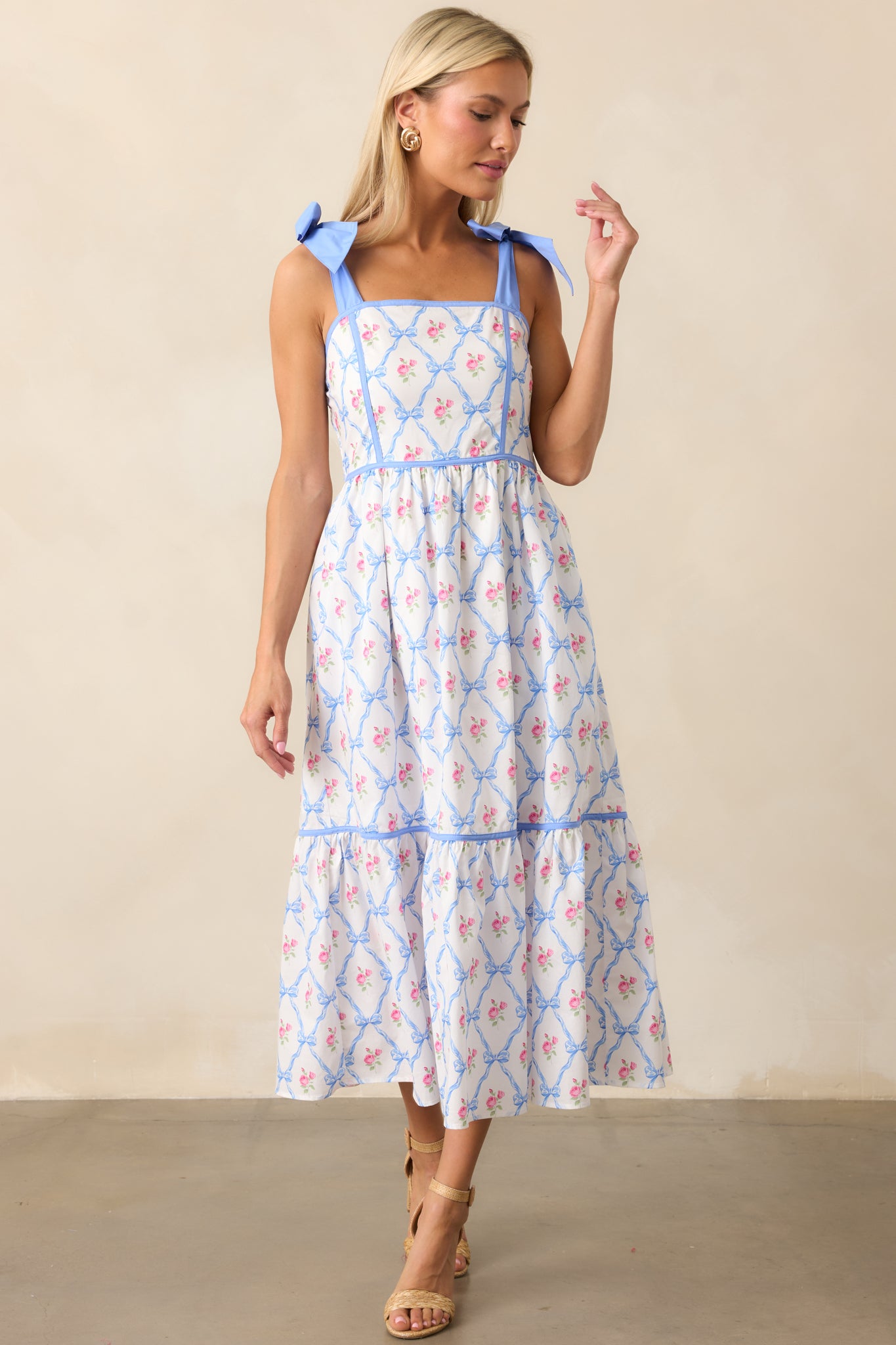 A view of the blue dress emphasizing the self-tie ribbon straps, square neckline, and smocked back. The functional pockets offer both style and functionality.