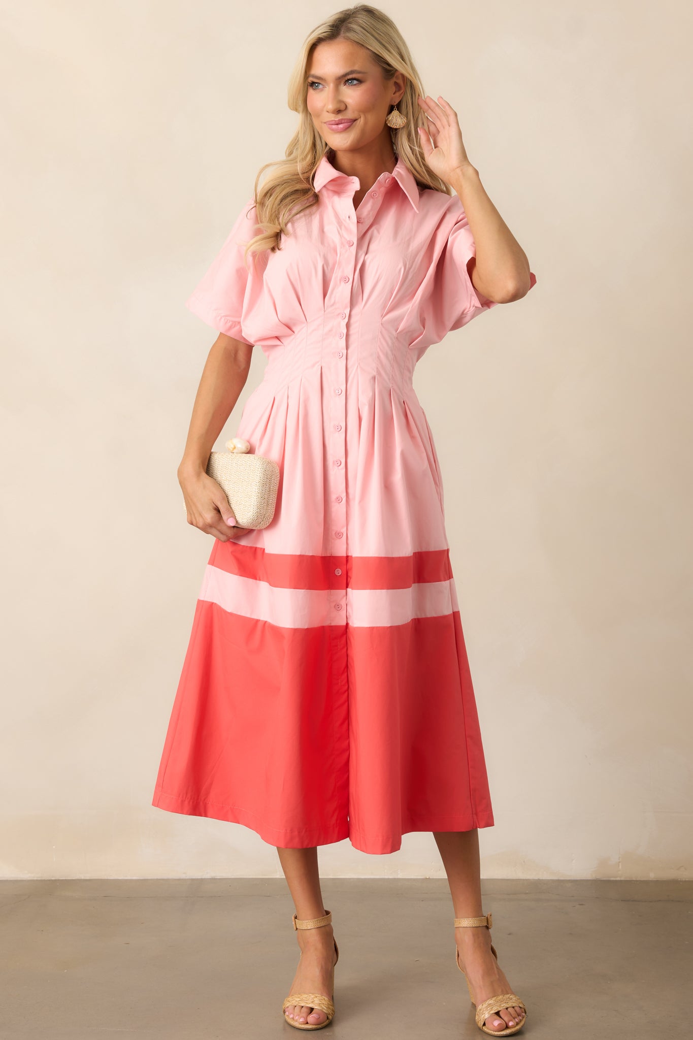 A full view of the pink midi dress highlighting the collared neckline, button front, and flow of the coral color block skirt.