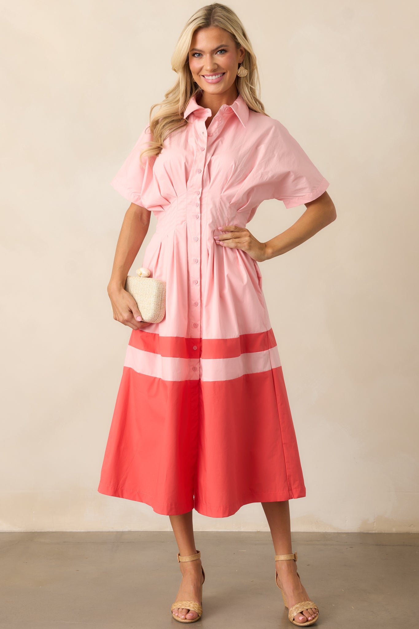 The pink midi dress from a slightly angled front view, focusing on the elastic waistband and the transition to the coral color block skirt.