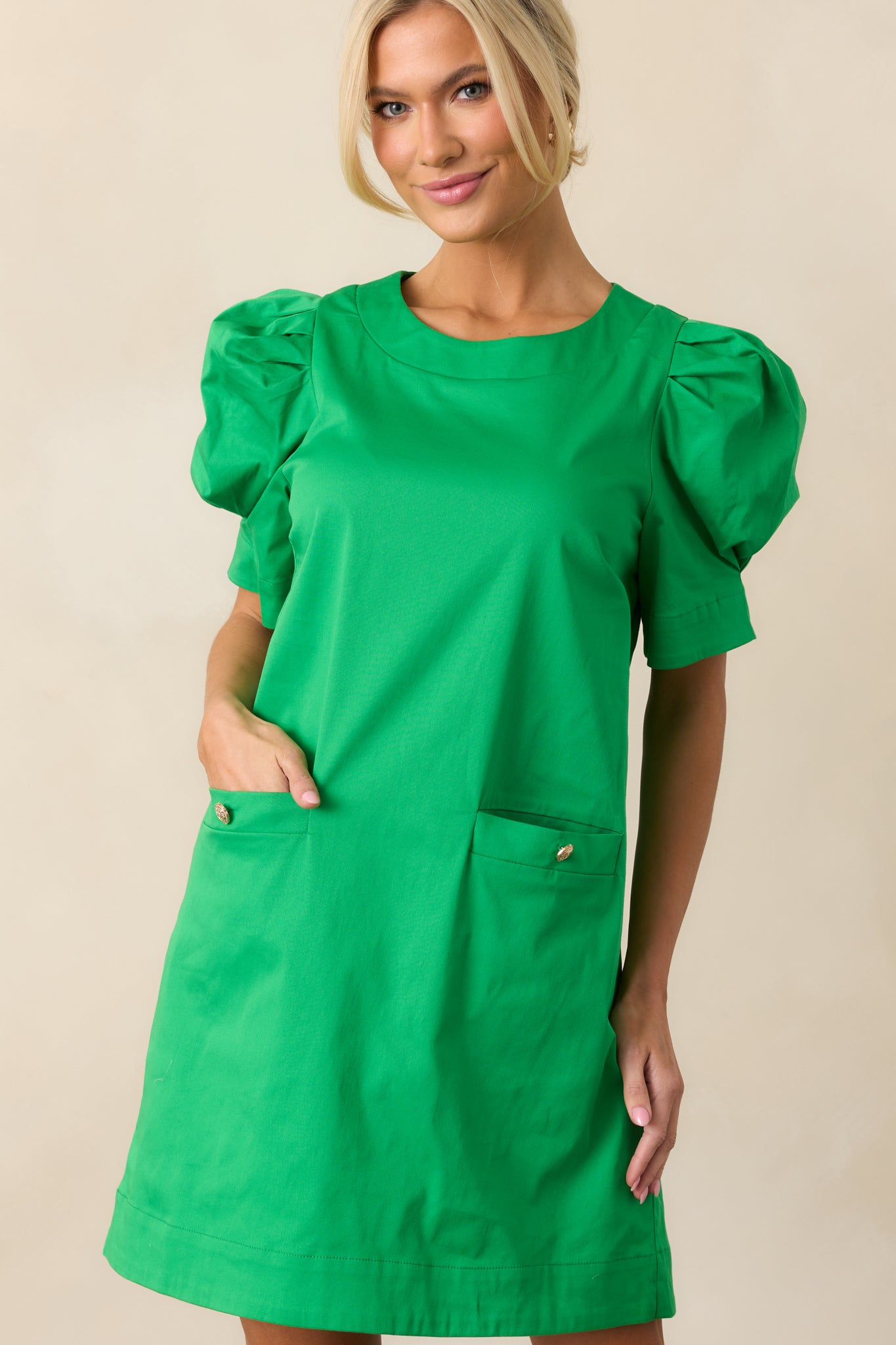 The functional front pockets on this green dress offer both style and practicality, complementing the A-line cut for a balanced design.