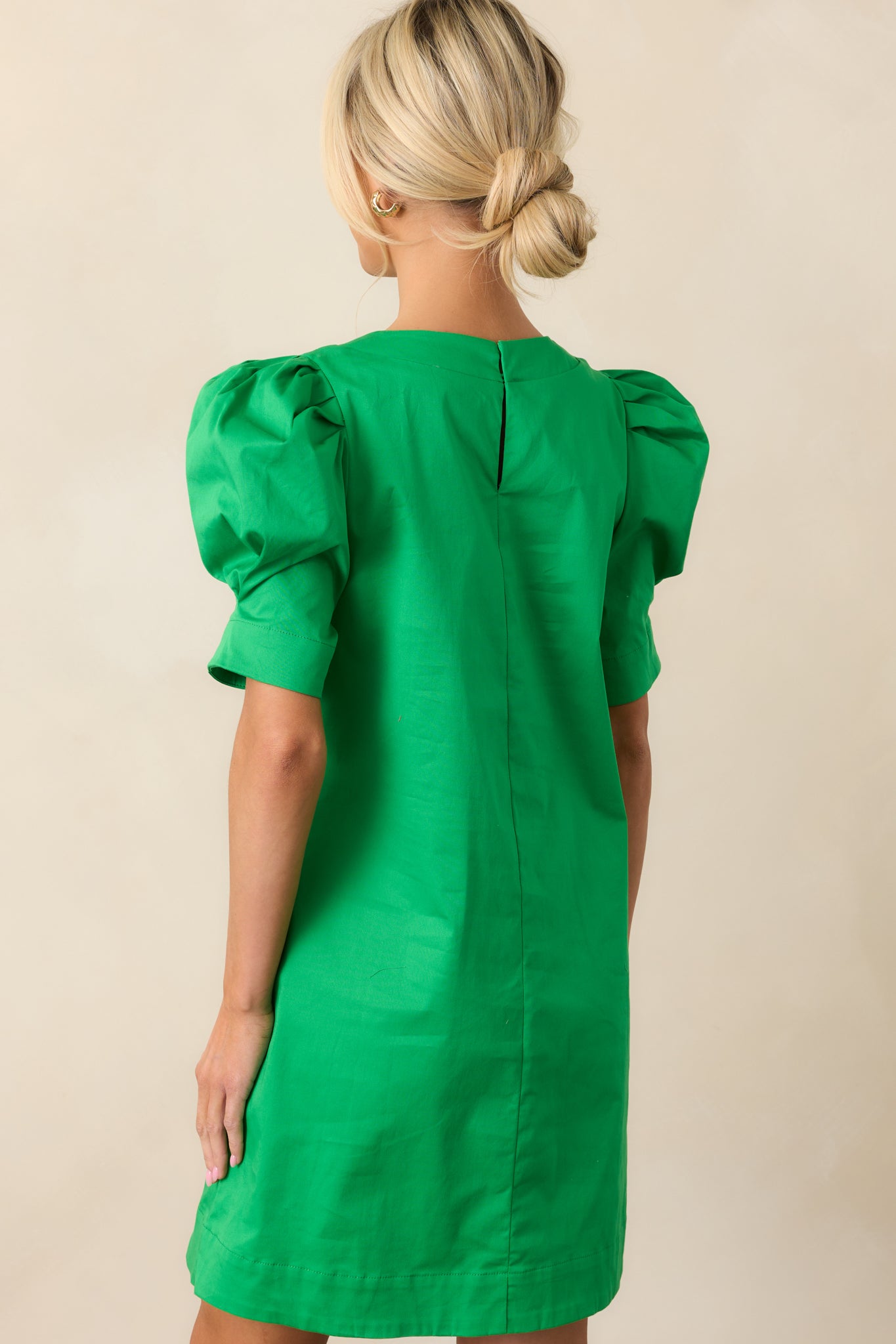 The back of this green mini dress highlights its clean, simple design, with the A-line shape continuing from front to back for a smooth, flattering look.