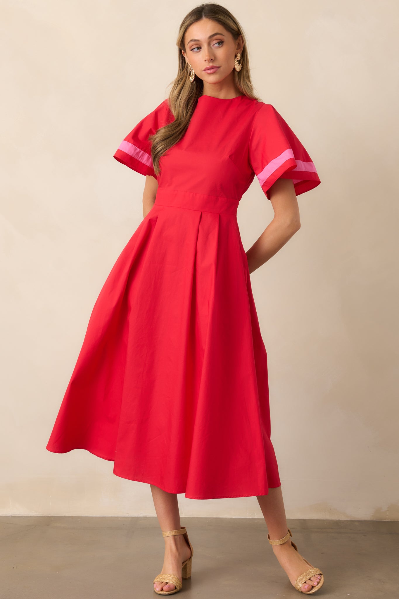 A playful red dress with a round neckline, puffy sleeves trimmed with pink stripes, and a defined waist for a feminine shape.