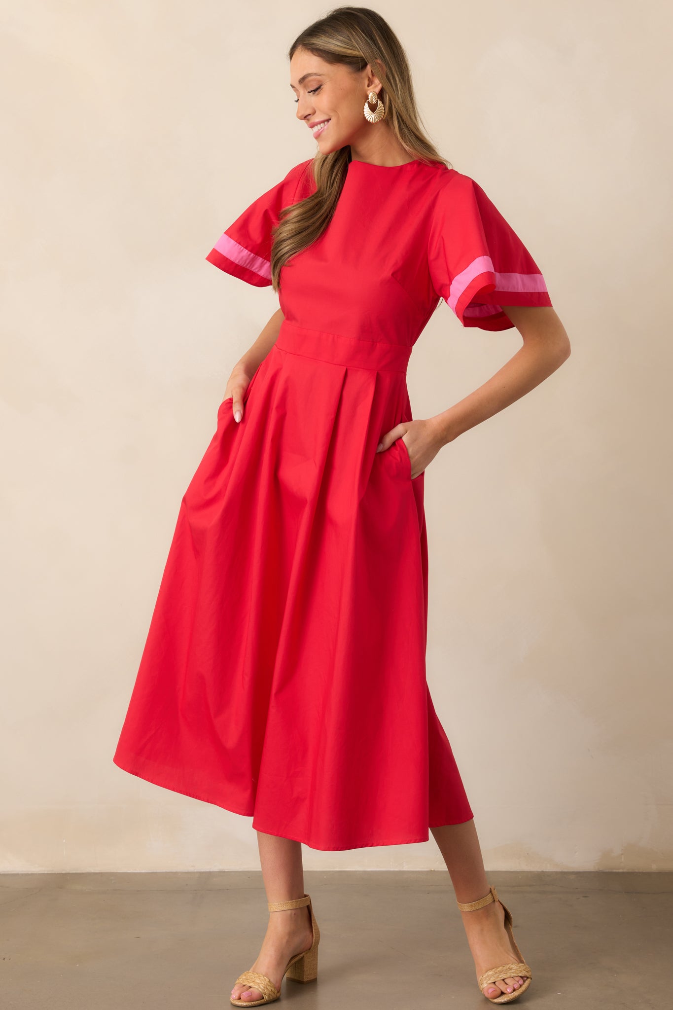 A vibrant red dress with puffy sleeves, pink-striped cuffs, and a waist-defining fit, creating a flattering and structured look.