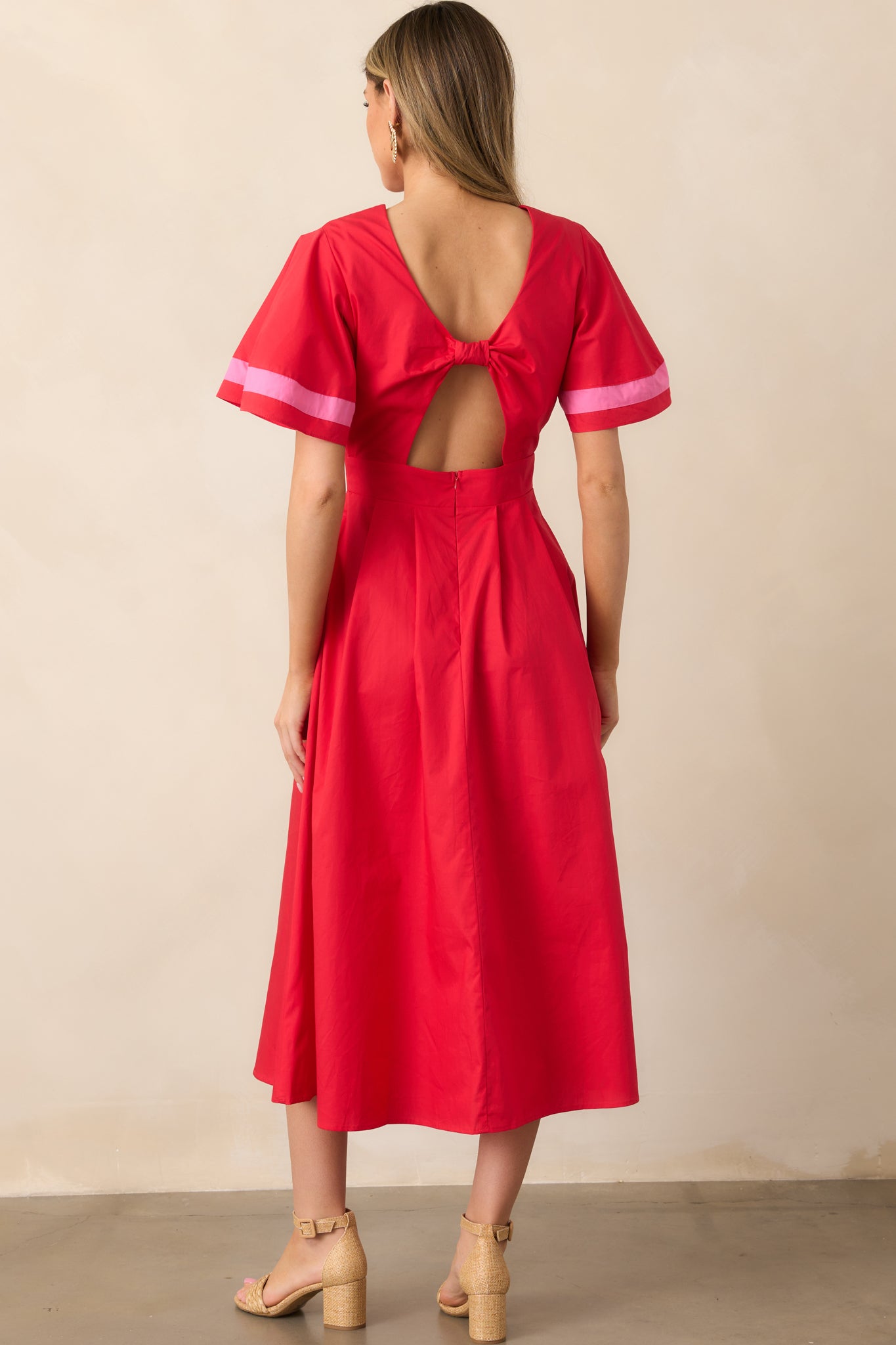 The back of this red dress features smooth lines with a fitted waist, and the pink stripes on the cuffs add a colorful detail.