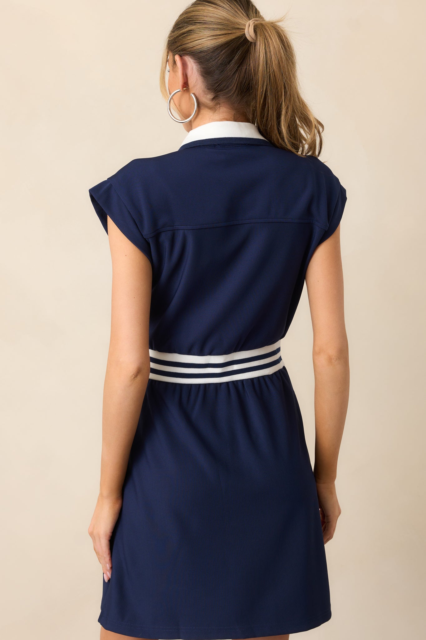 The back of this navy dress showcases the clean lines of the zipper front and simple cap sleeves for a sleek finish.