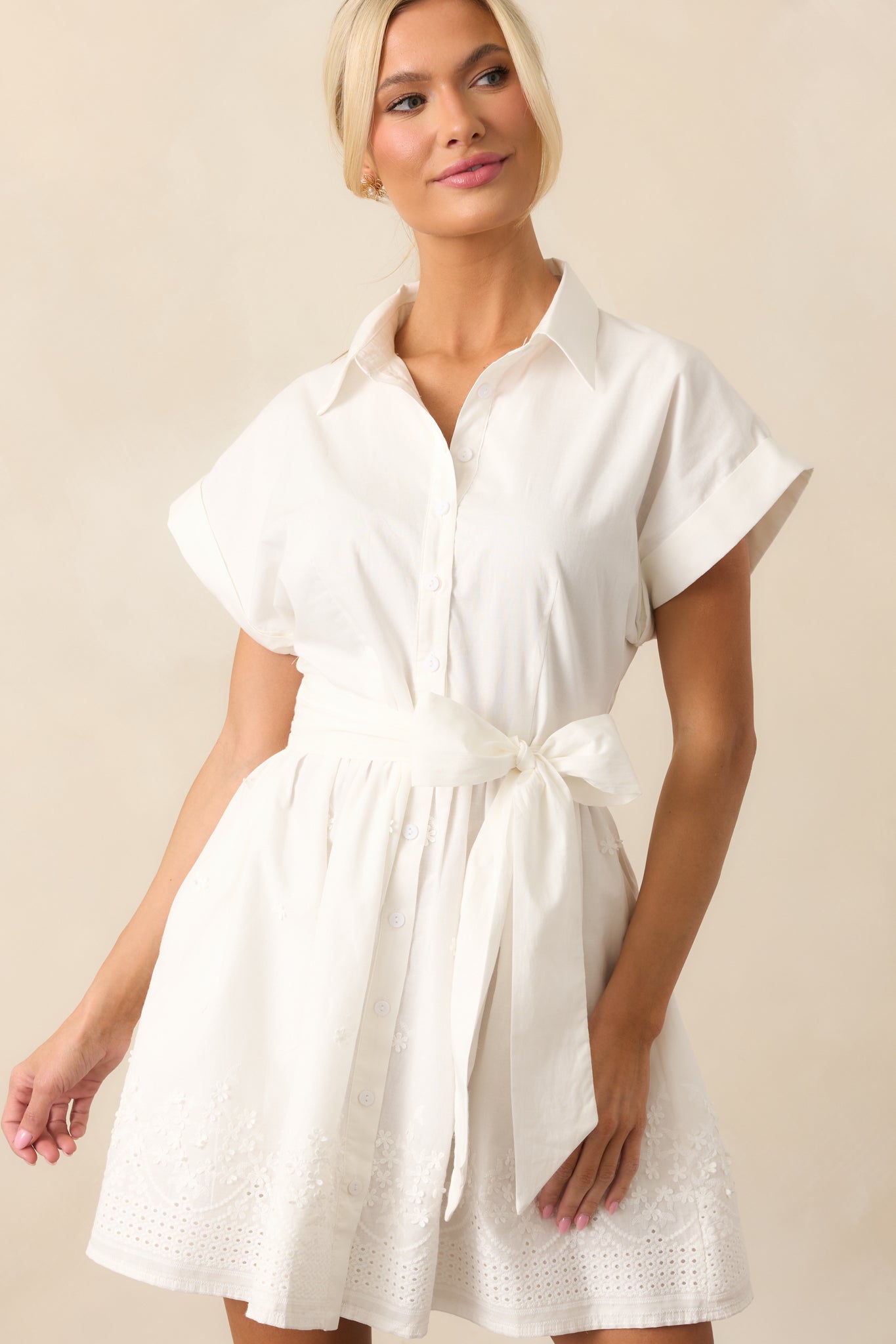  A cropped angle that captures the fine embroidered detailing along the hem and the button front closure, showcasing the chic simplicity of the dress.