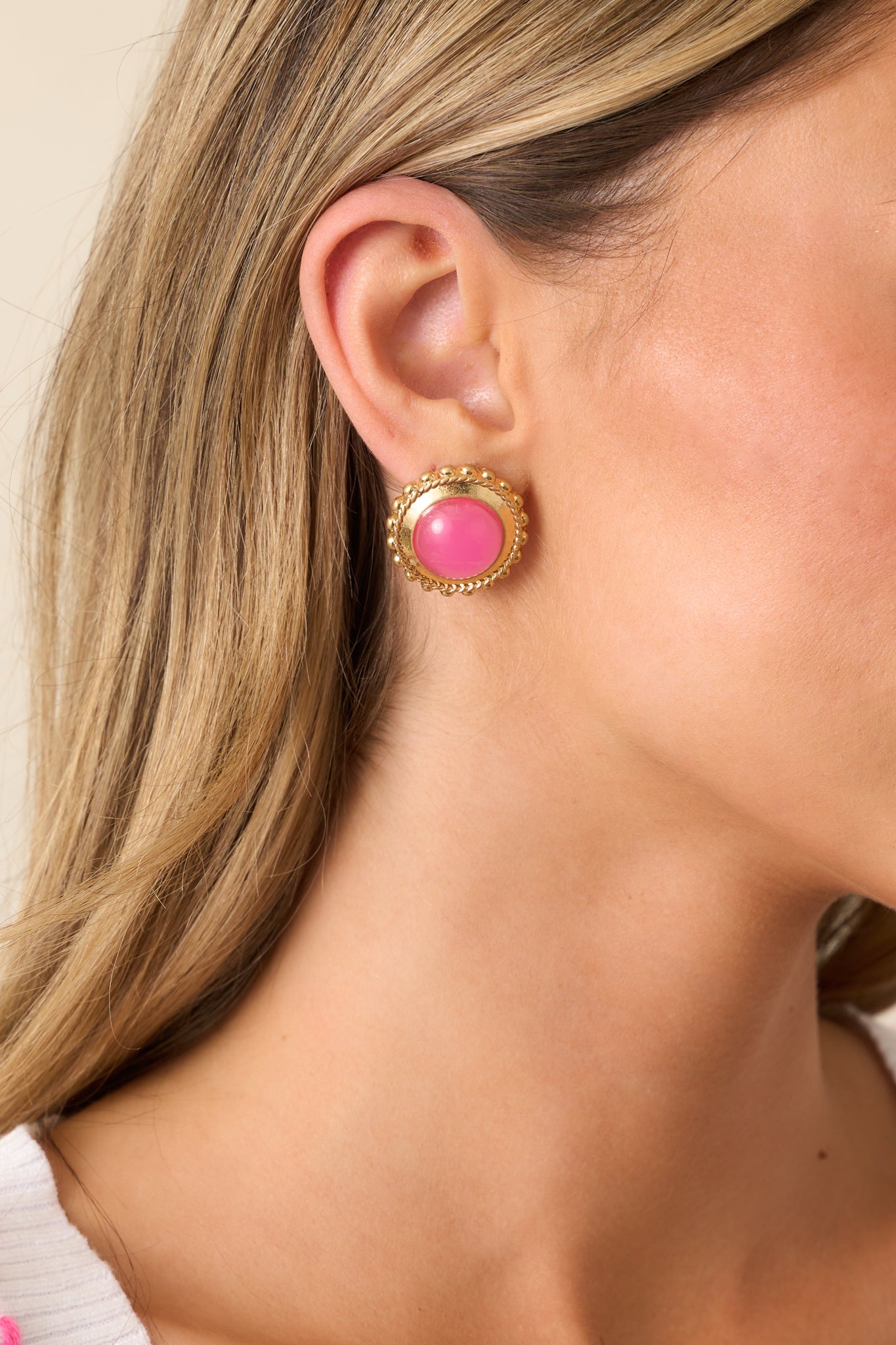 Pink and gold earrings with a circular shape, featuring a large pink center bordered by a gold frame and a beaded gold edge.