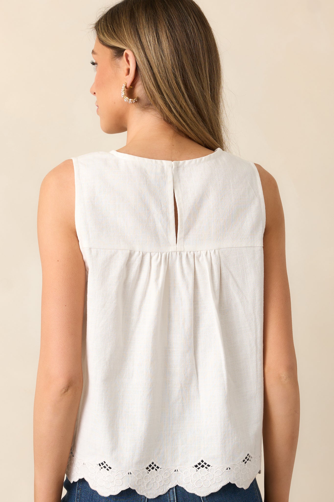 The back view of this white blouse with a keyhole closure and scalloped hem, offering a clean and classic silhouette.