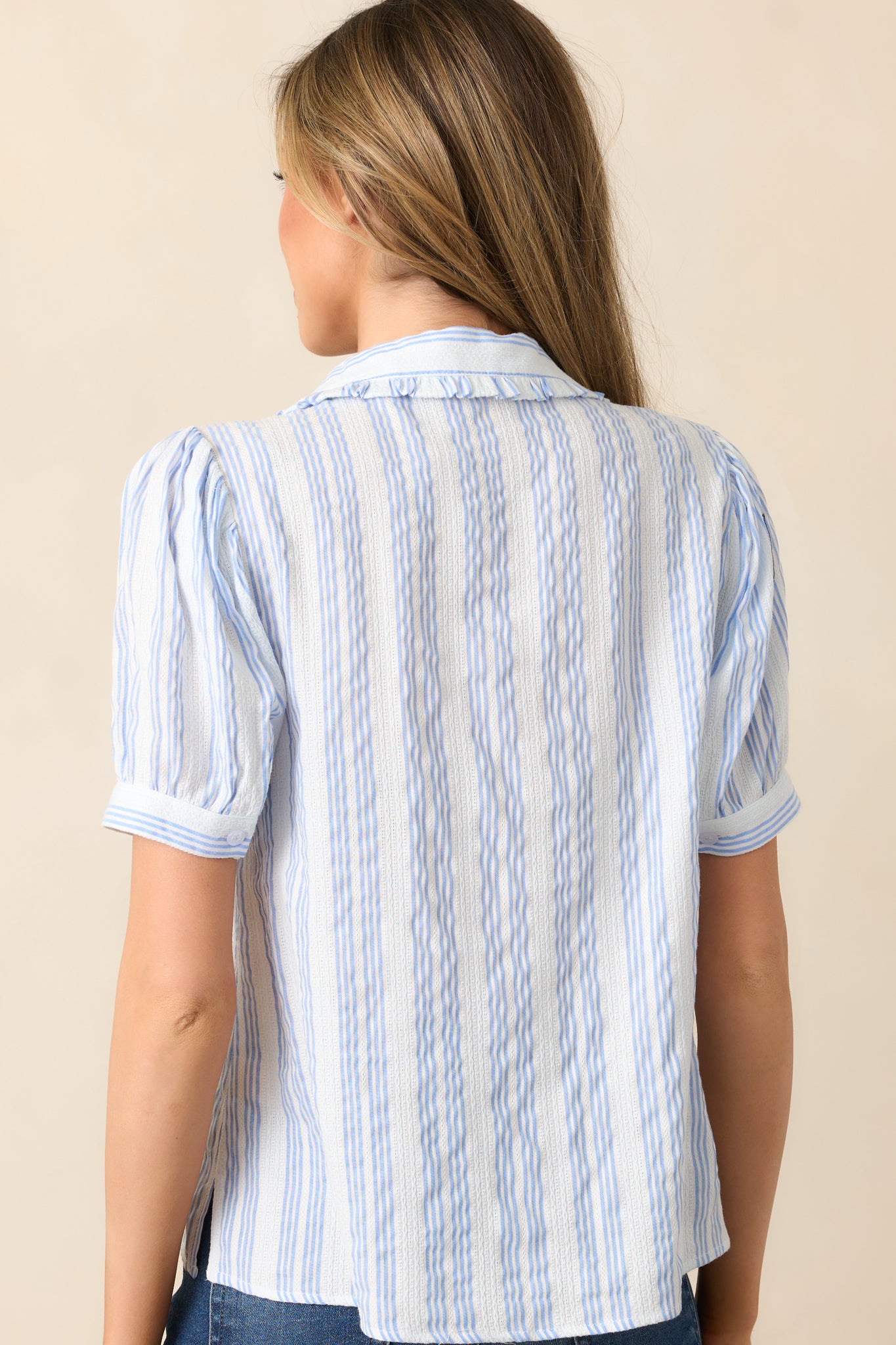 The back of the blouse features the subtle stripe print, a smooth drape, and a continuation of the embroidered accents.