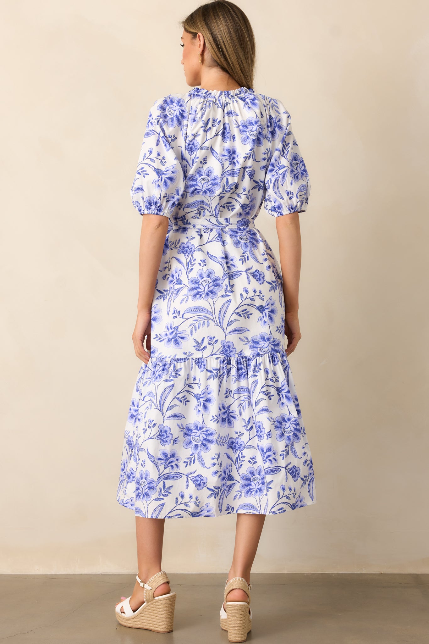 The back of the dress features a continuous floral print, a flowing silhouette, and subtle structure in the short sleeves.