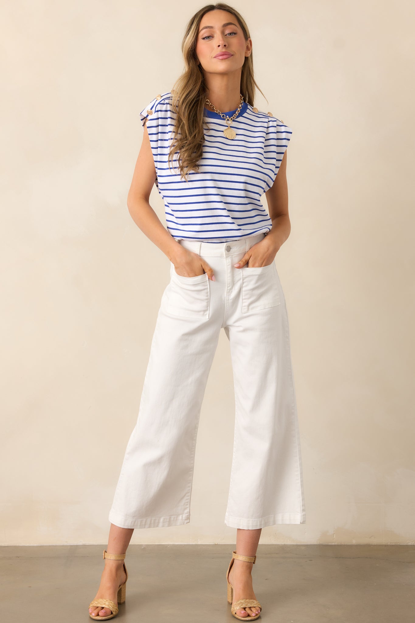 Front angled view of white pants featuring a high waisted design, classic button & zipper closure, belt loops, functional front pockets, faux back pockets, and a wide leg design.