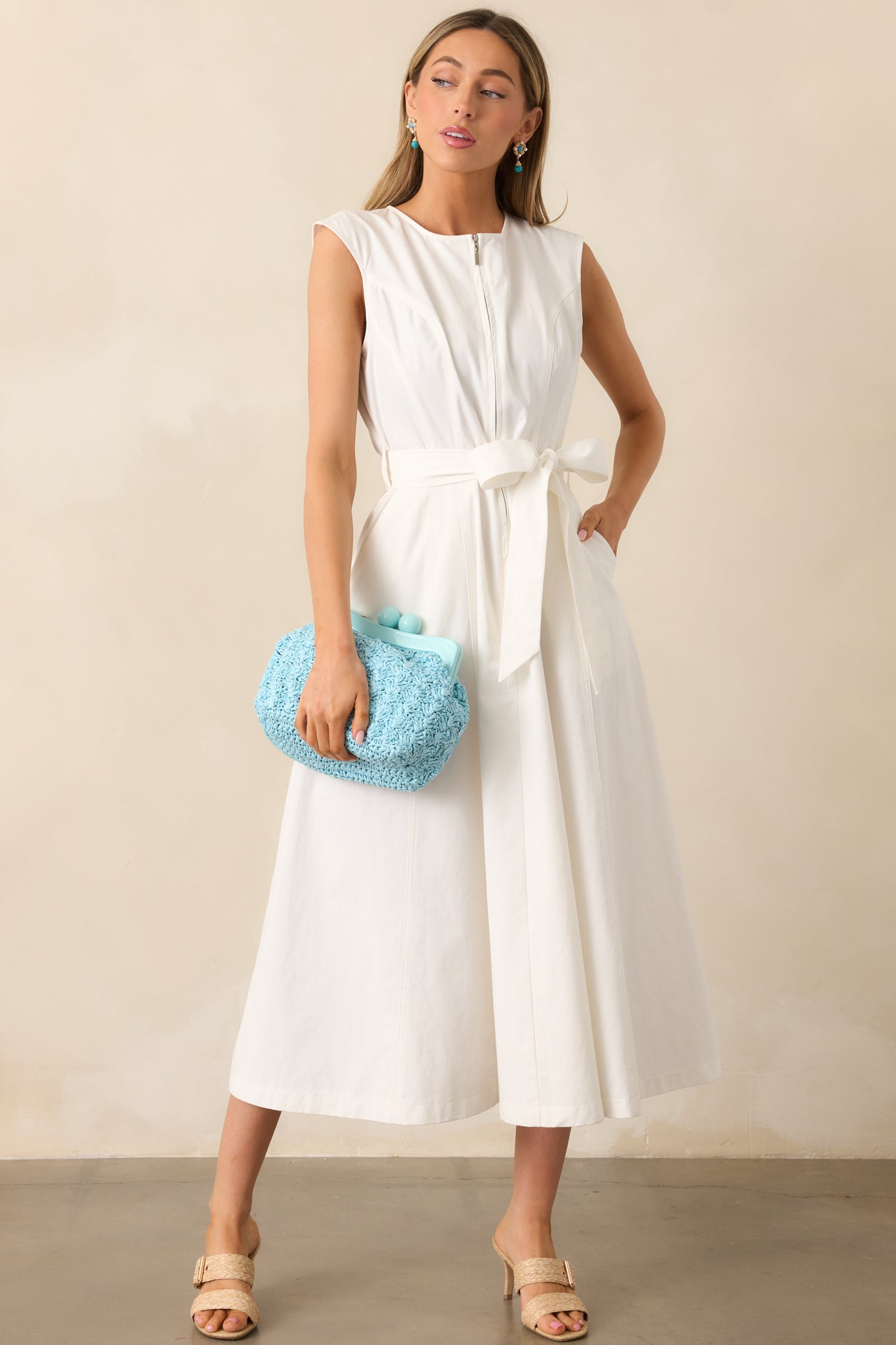 The flowing silhouette of the midi-length skirt enhances the dress’s airy and lightweight feel.