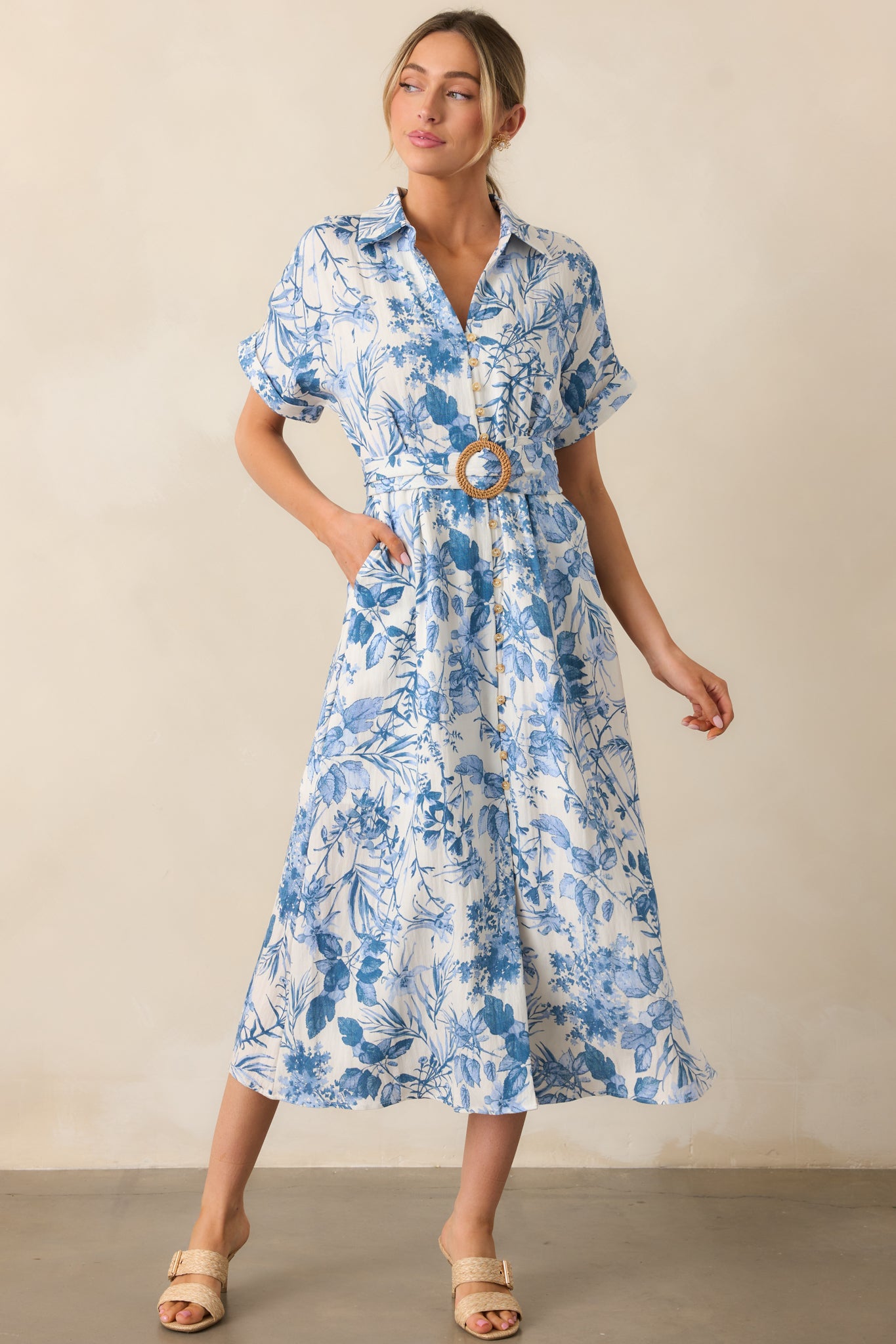 A blue midi dress, highlighting the collared V-neckline, button-down front, and waist-cinching pull-through belt.