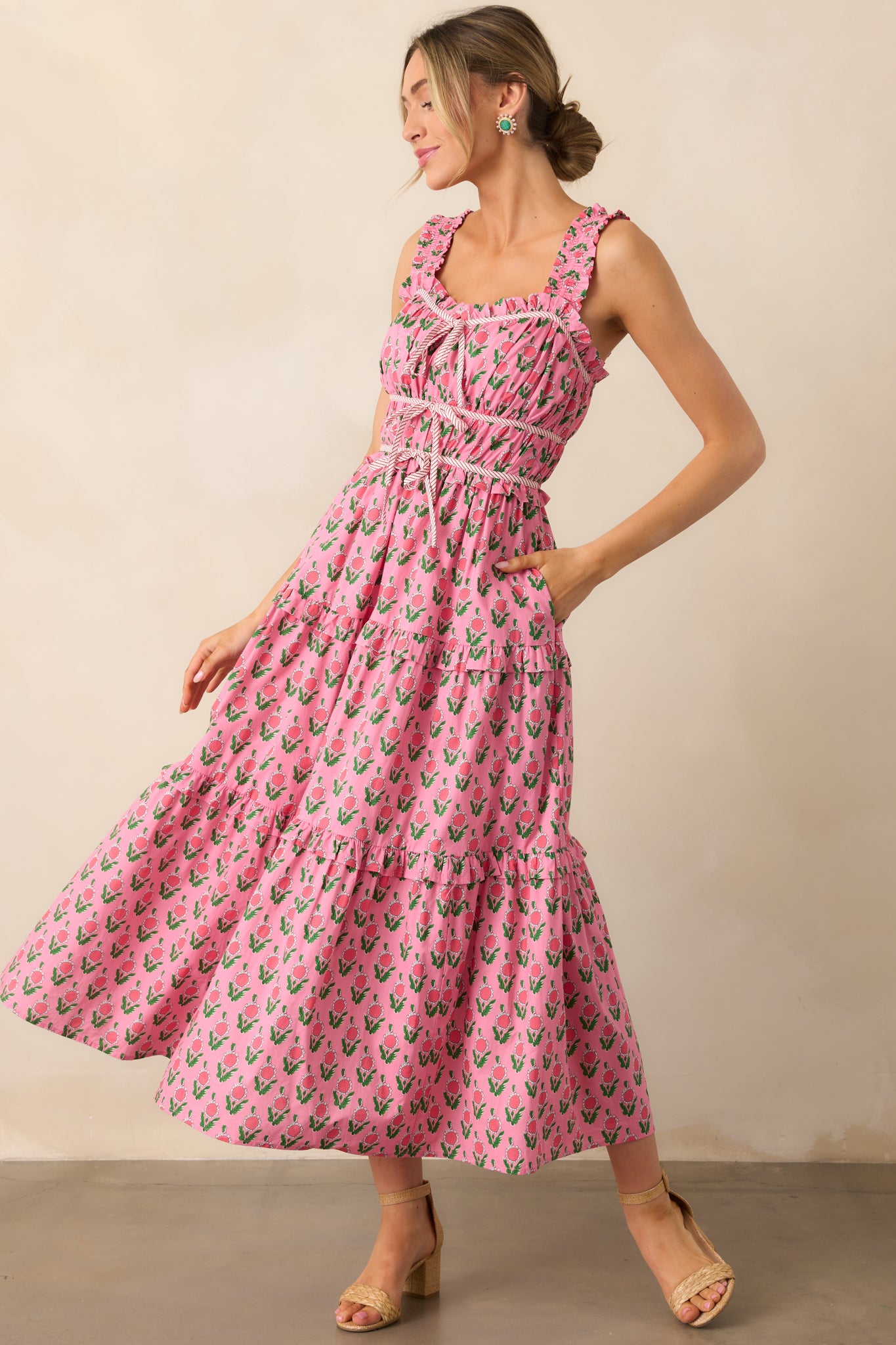 The dress showcases two functional side pockets, a three-tiered design at the waist, and delicate bow tie details that add charm and a playful touch