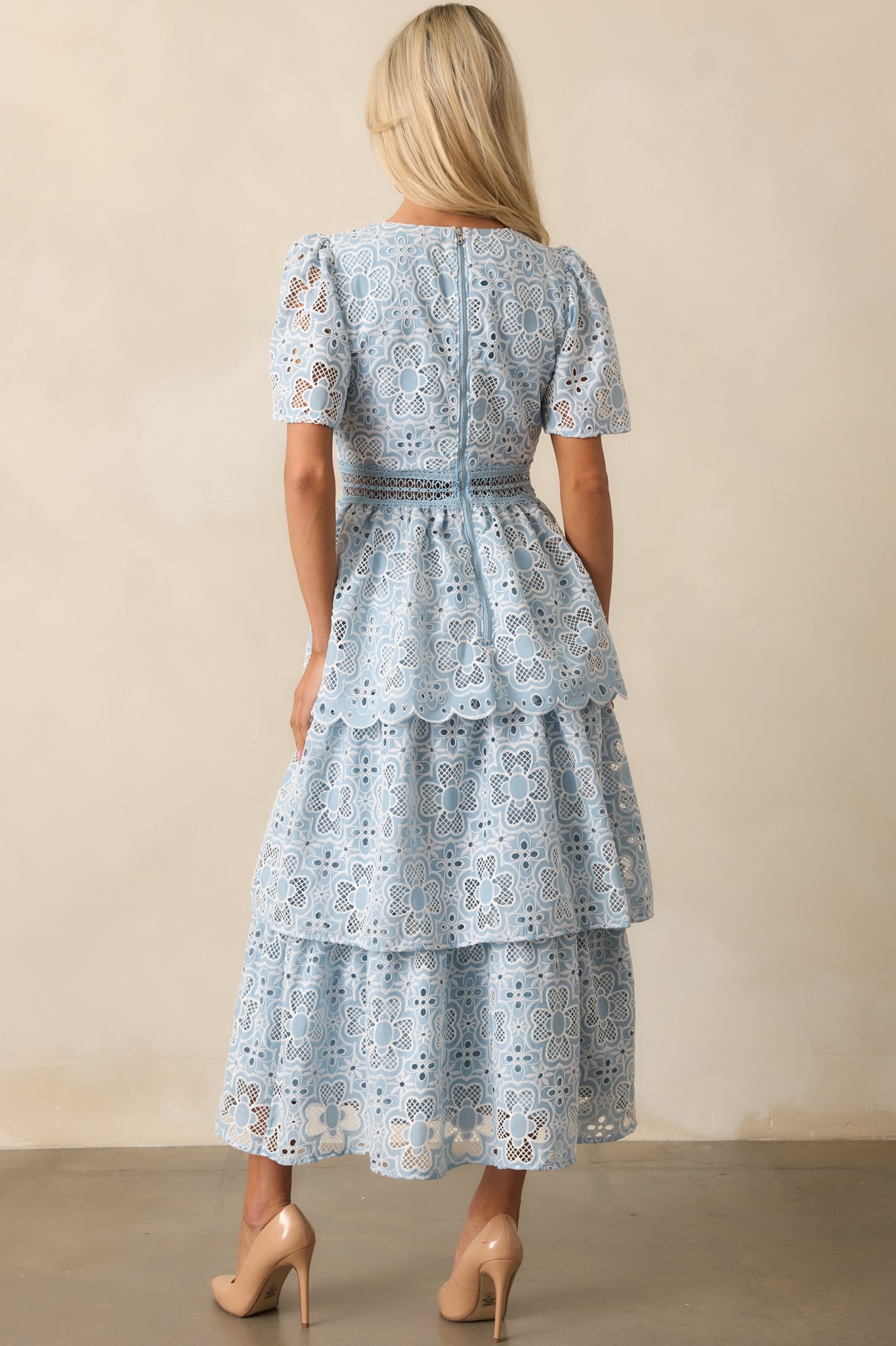 The blue dress from the back, featuring a functional zipper and a softly cascading tiered skirt.