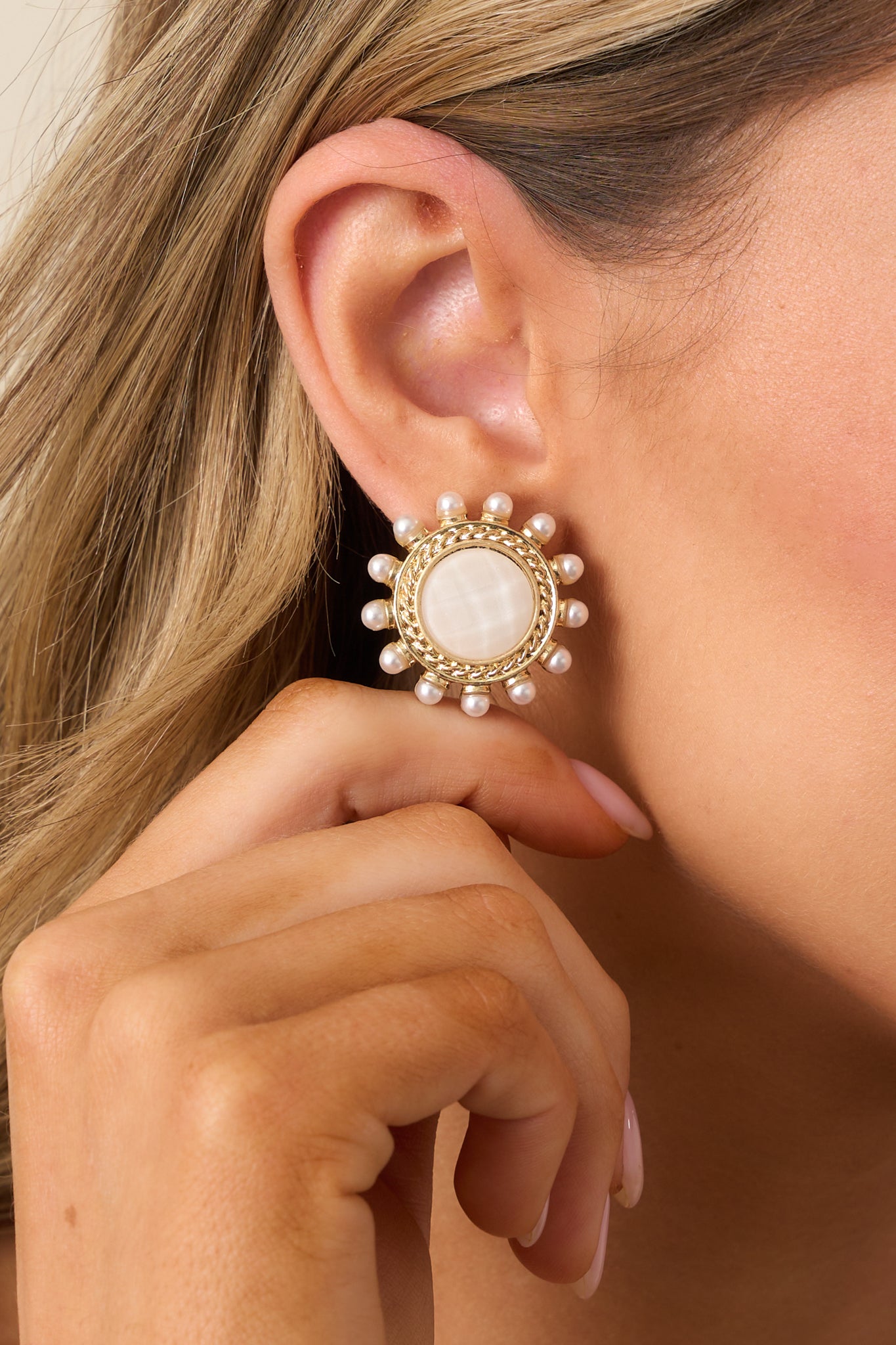 A detailed view of the white and gold earrings, highlighting the intricate gold braided border, the ivory faux pearls, and the pearlescent white middle for a luxurious look.