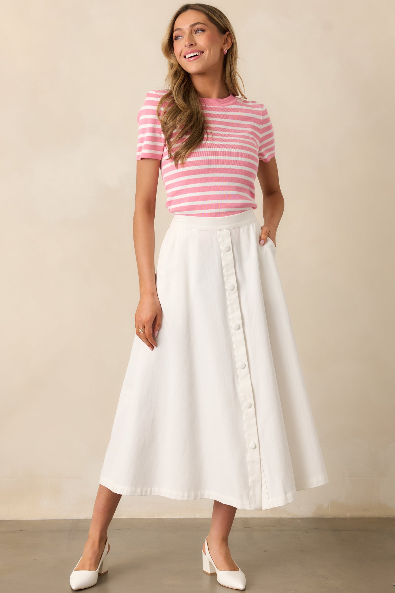 Featuring a flattering high-waisted cut, this ivory midi skirt incorporates an elastic waistband and faux button details for a stylish finish.