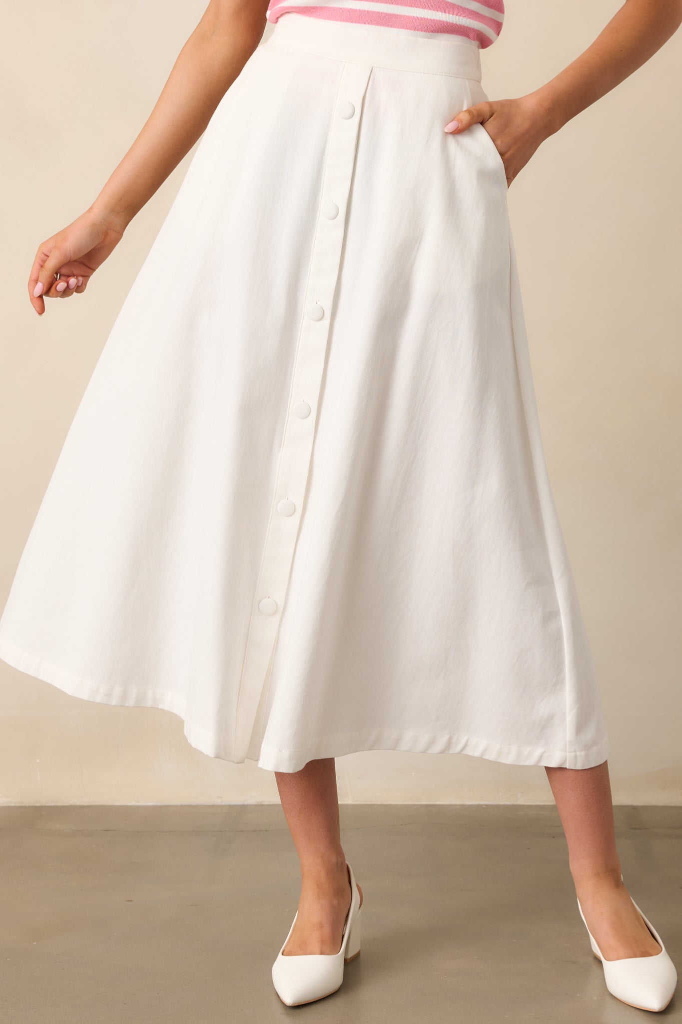 Zoomed in on the waist, this ivory midi skirt shows off its high-waisted design with faux button accents for a refined look.