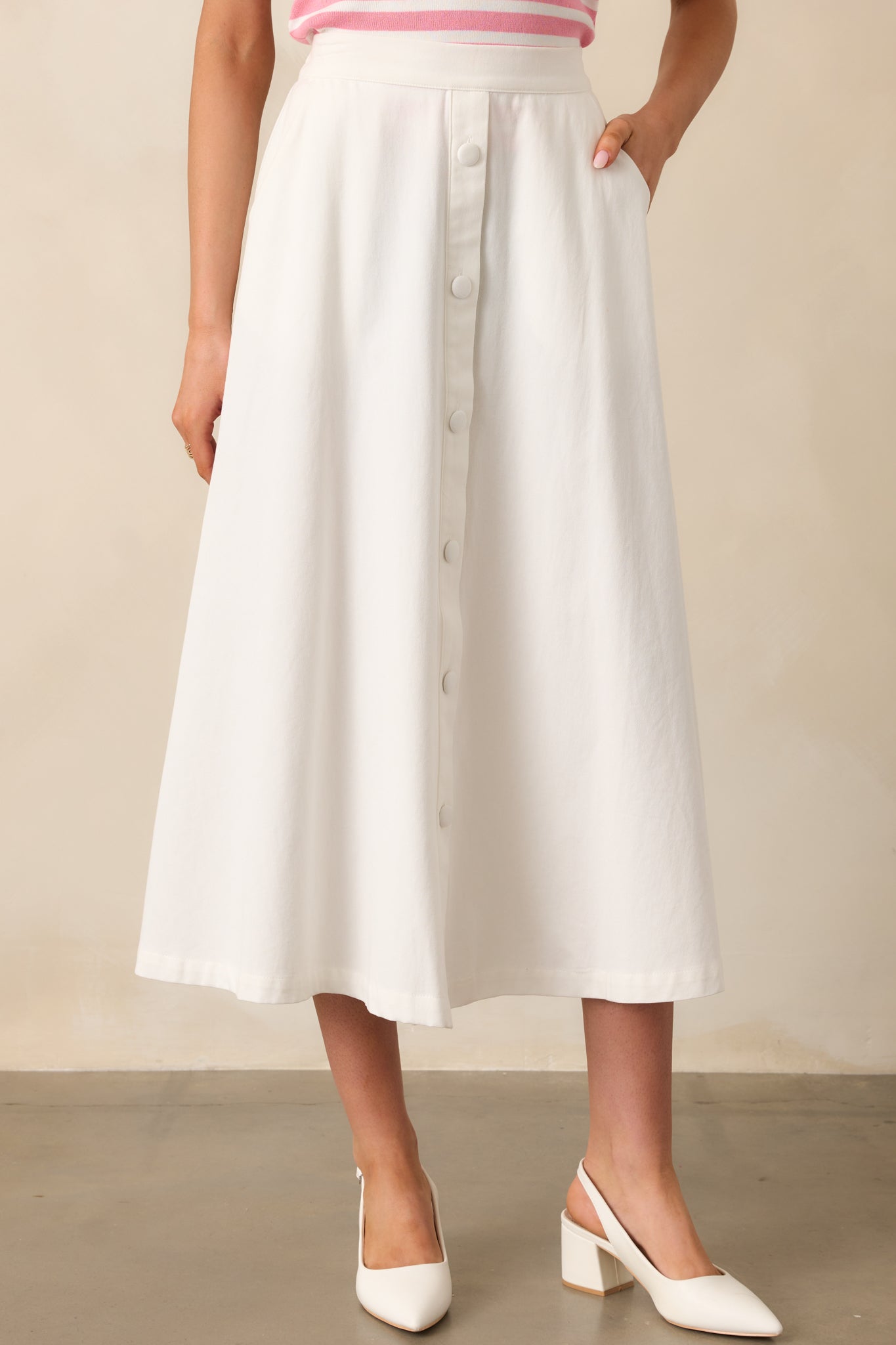 With a flattering high-waisted silhouette, this ivory midi skirt is styled with faux button details down the front for a touch of classic charm.