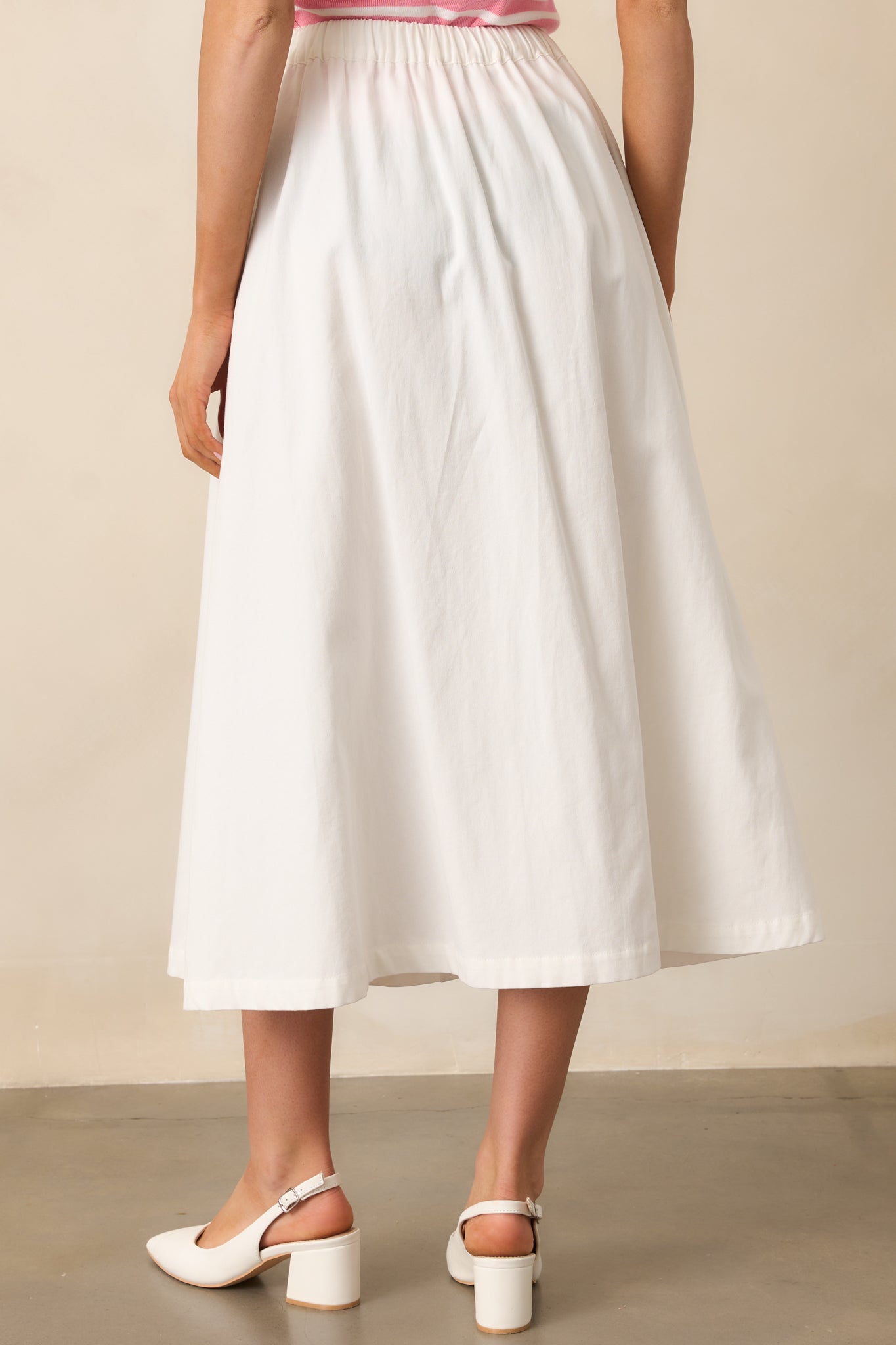 The back of this ivory midi skirt showcases the elastic insert at the waistband, offering both comfort and a seamless fit.