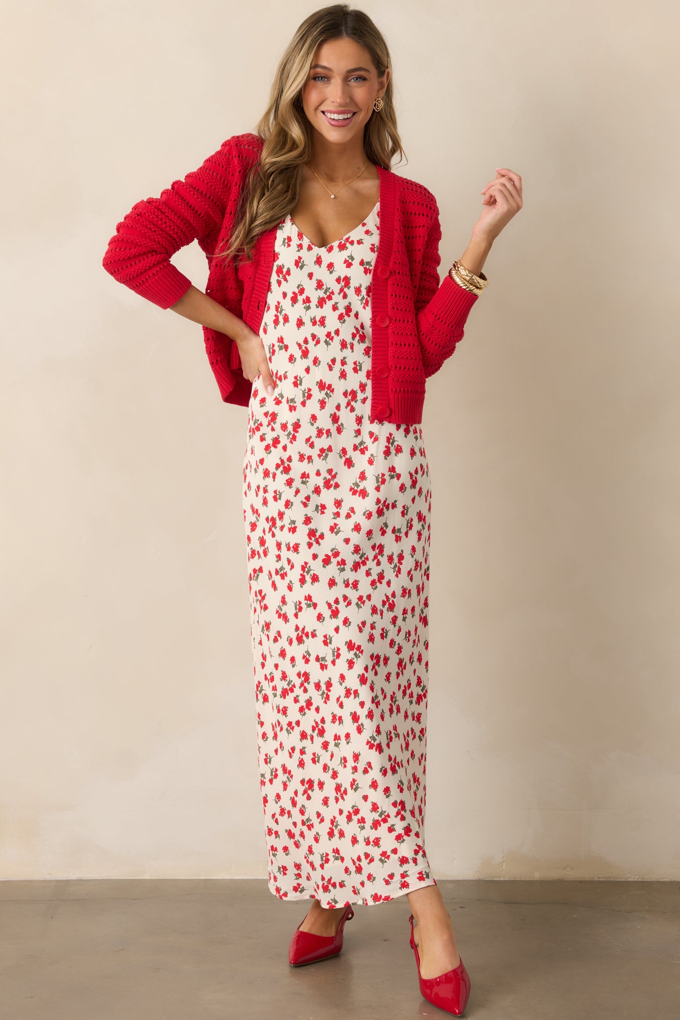 A full body photo showing the red cardigan's button front, ribbed bottom, and long sleeves. The open stitch pattern adds a layered design element that complements the relaxed fit.