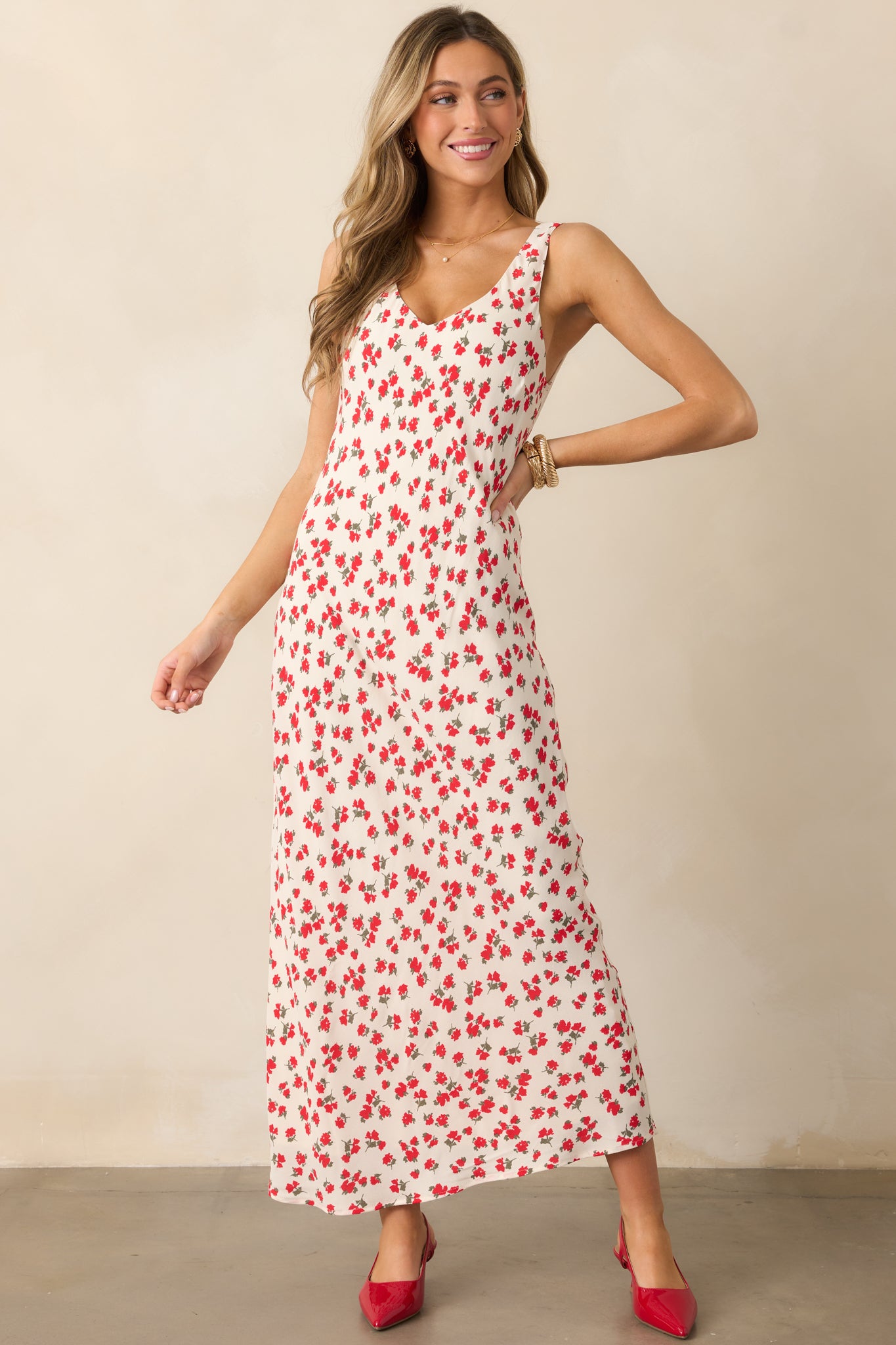 A full body view of the ivory dress with its v-neckline and delicate ditsy floral print, the maxi length cascading elegantly, and the sleeveless design showcasing its summer-ready look.