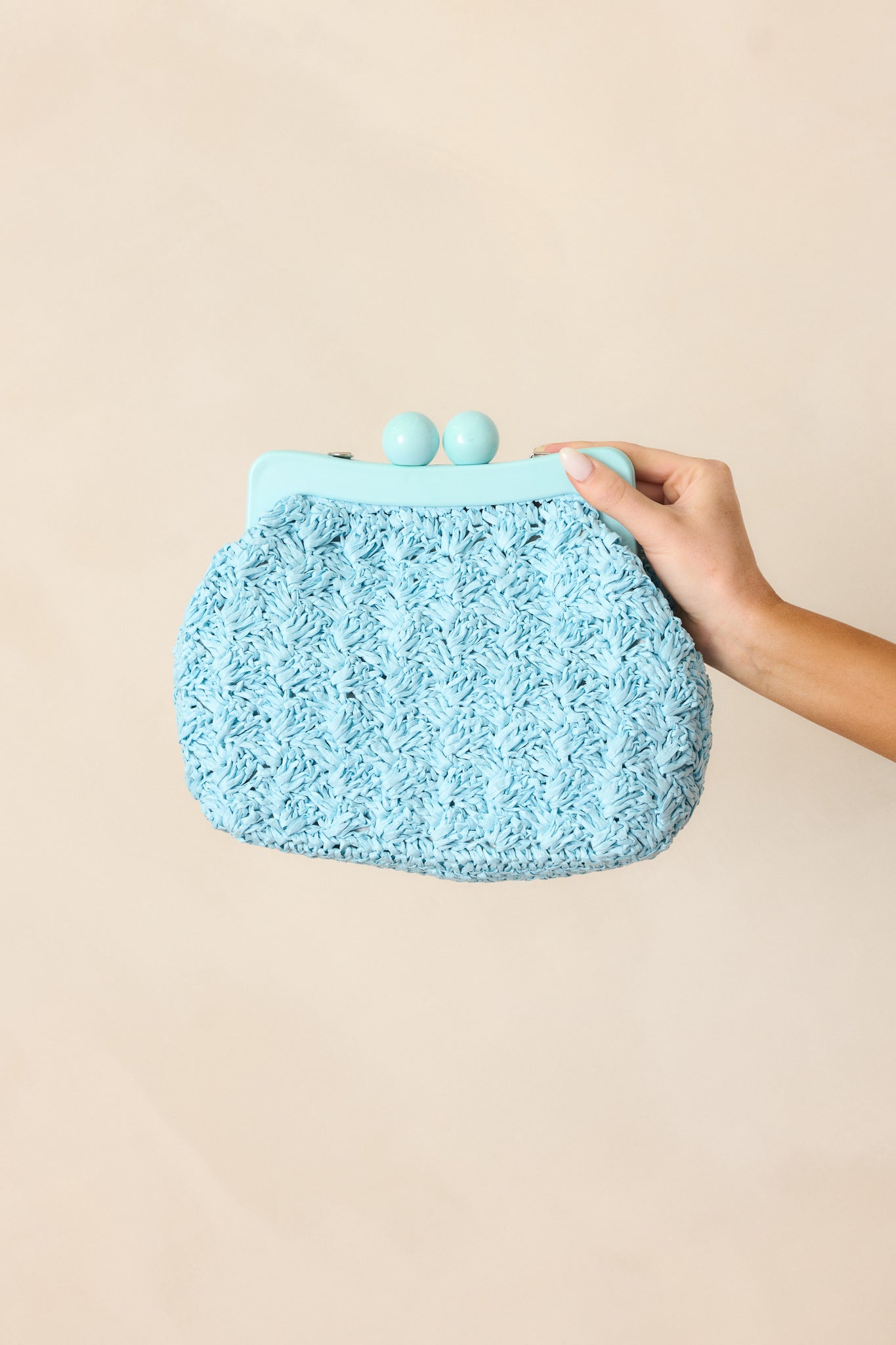 A full angle of the blue woven clutch with a magnetic clasp for extra closure, showcasing the rounded design.