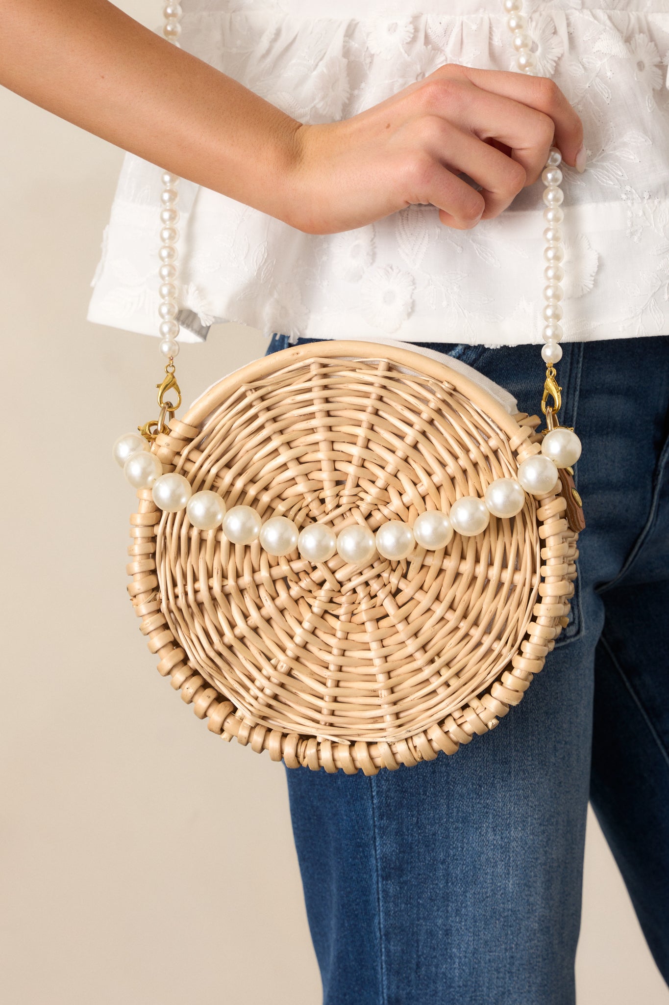 A closer shot of the handbag, focusing on the faux pearl straps, gold hardware, and the drawstring closure, capturing its refined design details.