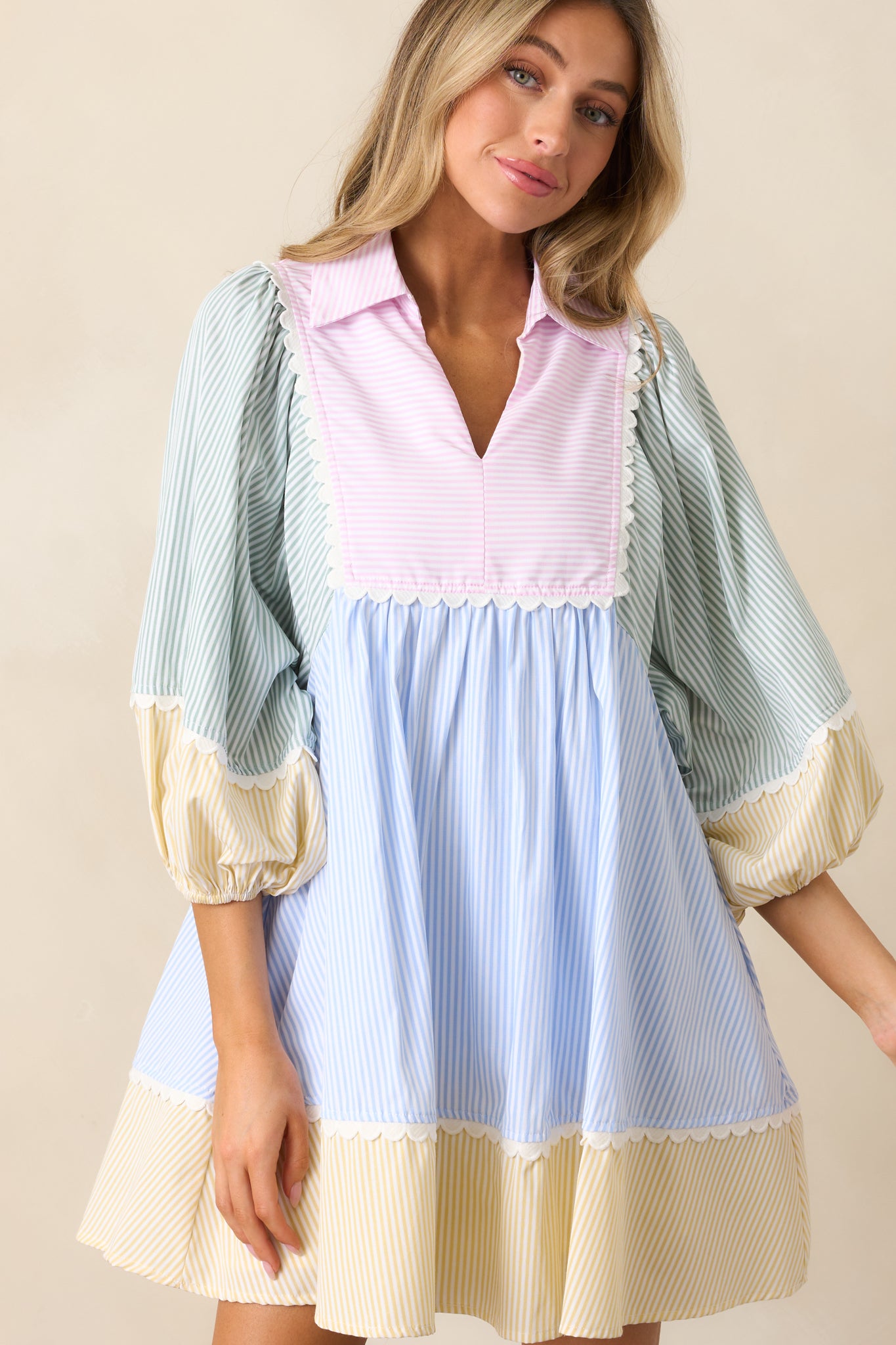  A detailed view of the dress' ruffle detailing and color block design, with emphasis on the v-neck and collared neckline, and the functional pockets.