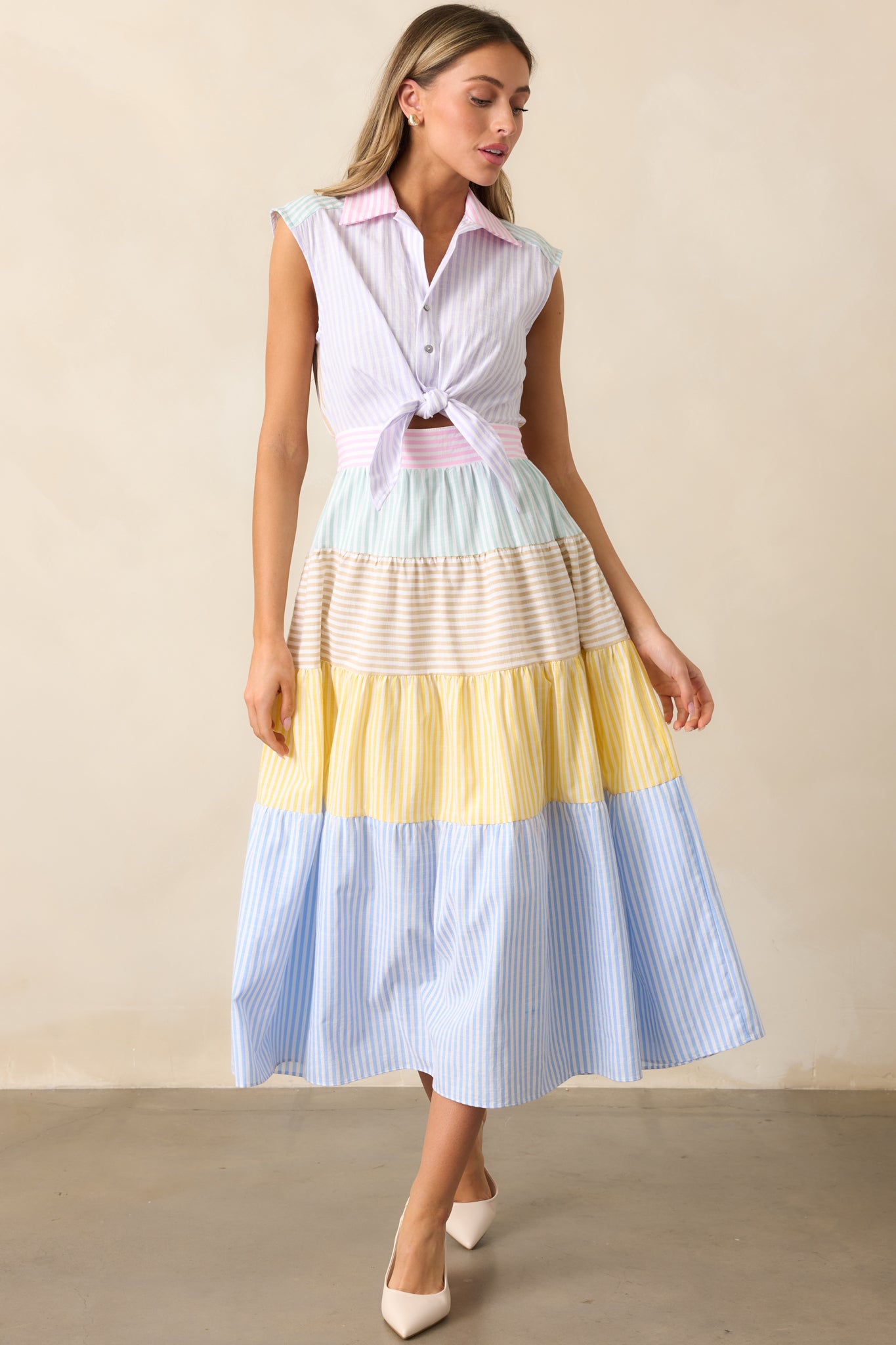 The lavender dress features a collared neckline, color block design, and button front with front tie details, paired with a flowing tiered skirt for added elegance.