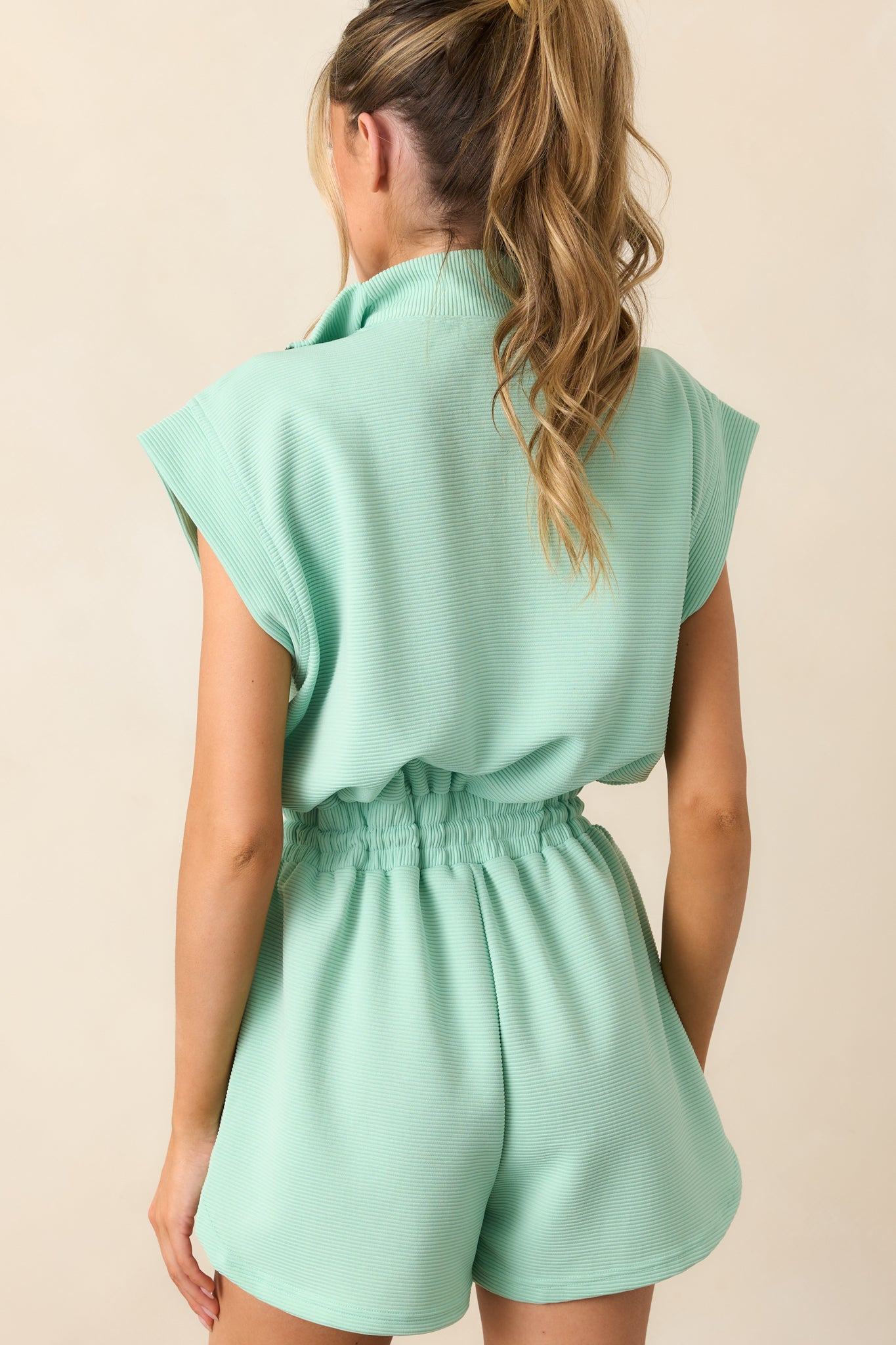 The back of the mint romper, showing the smooth ribbed texture, cap sleeves, and zip closure details.