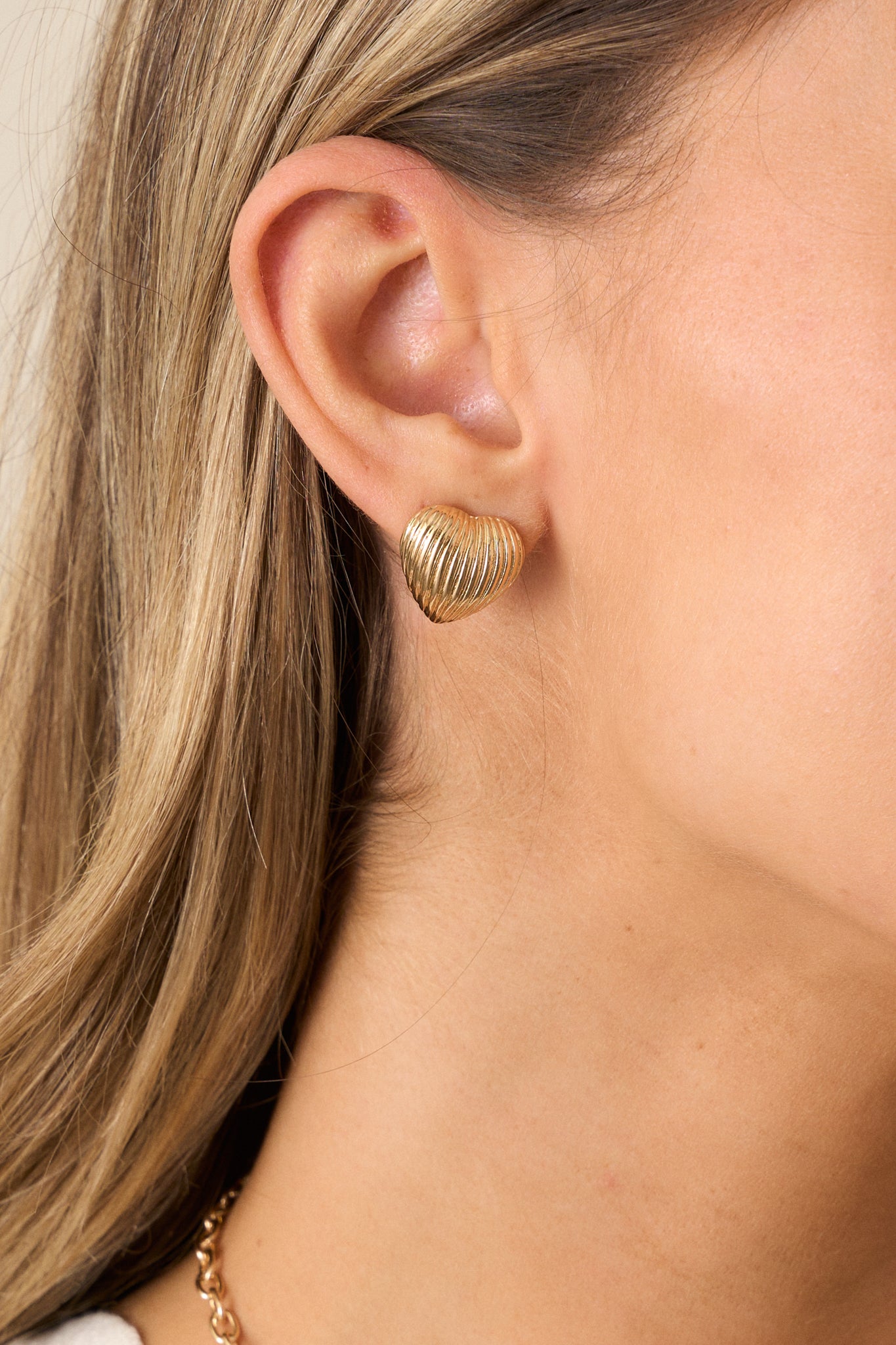 A close-up of the earring’s textured gold front and secure back posting, emphasizing the intricate detailing and smooth finish.