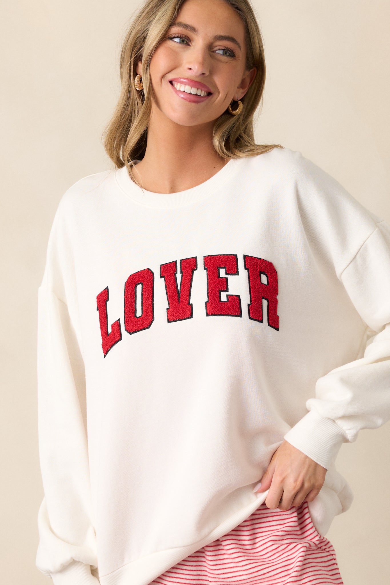 A cropped view of the ivory sweatshirt focusing on the crew neckline and the "LOVER" script, highlighting the soft texture of the fabric.