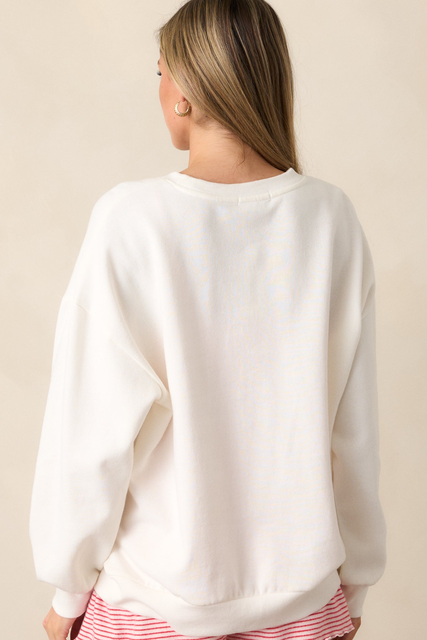 A back view of the ivory sweatshirt showing the relaxed fit and long sleeves with ribbed cuffs, highlighting the simplicity and softness of the design.