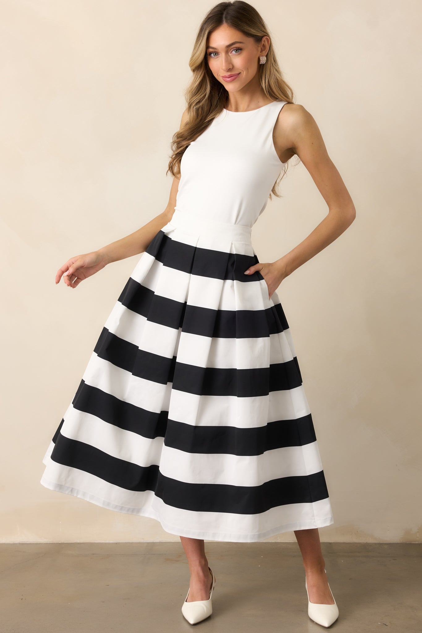 This black & white midi skirt features a high waisted design, a discrete side zipper, a thick waistline and functional hip pockets.