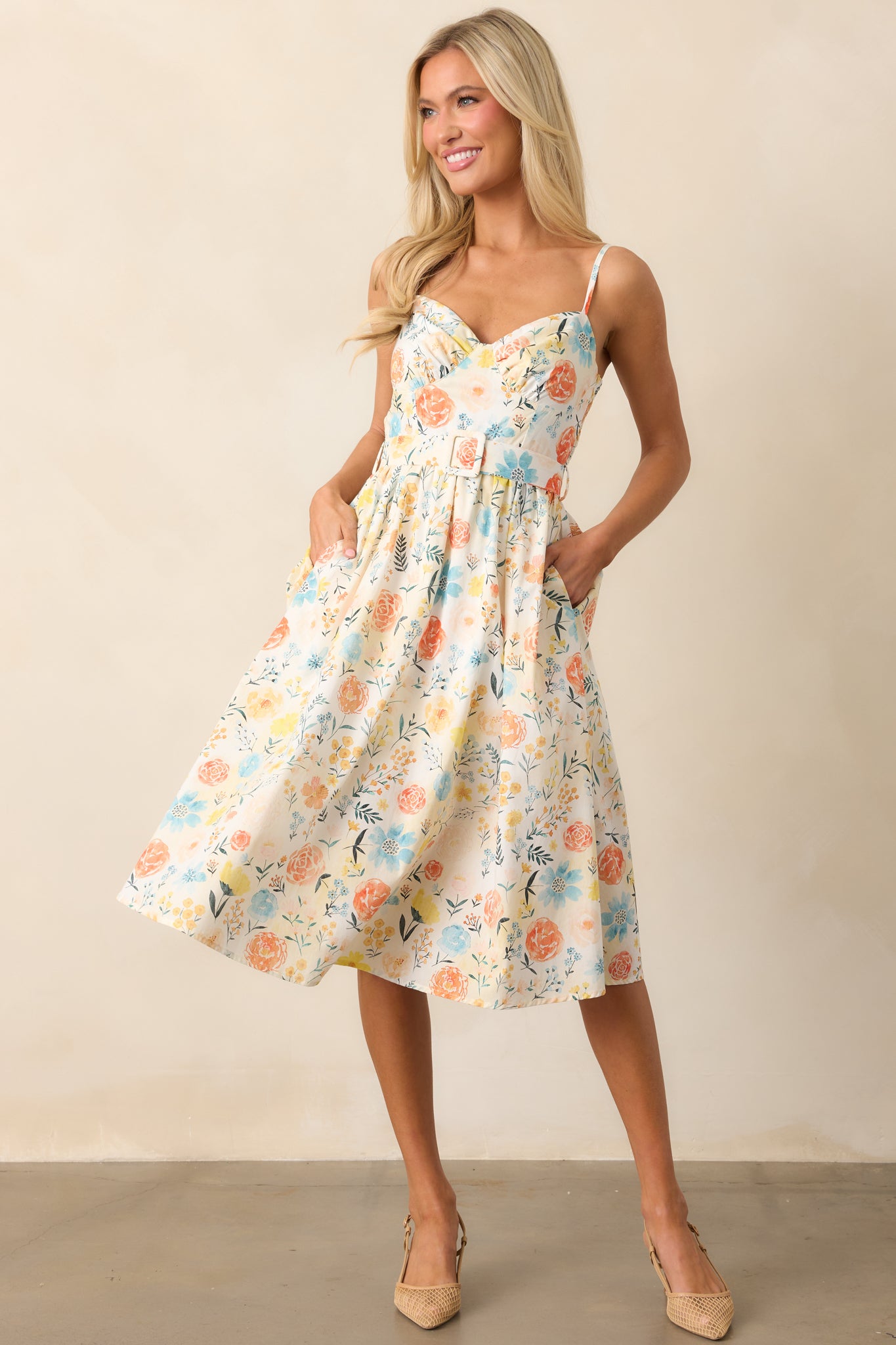 A front view of the ivory dress featuring a colorful floral print, an optional matching belt, and adjustable straps, offering a soft, feminine look.