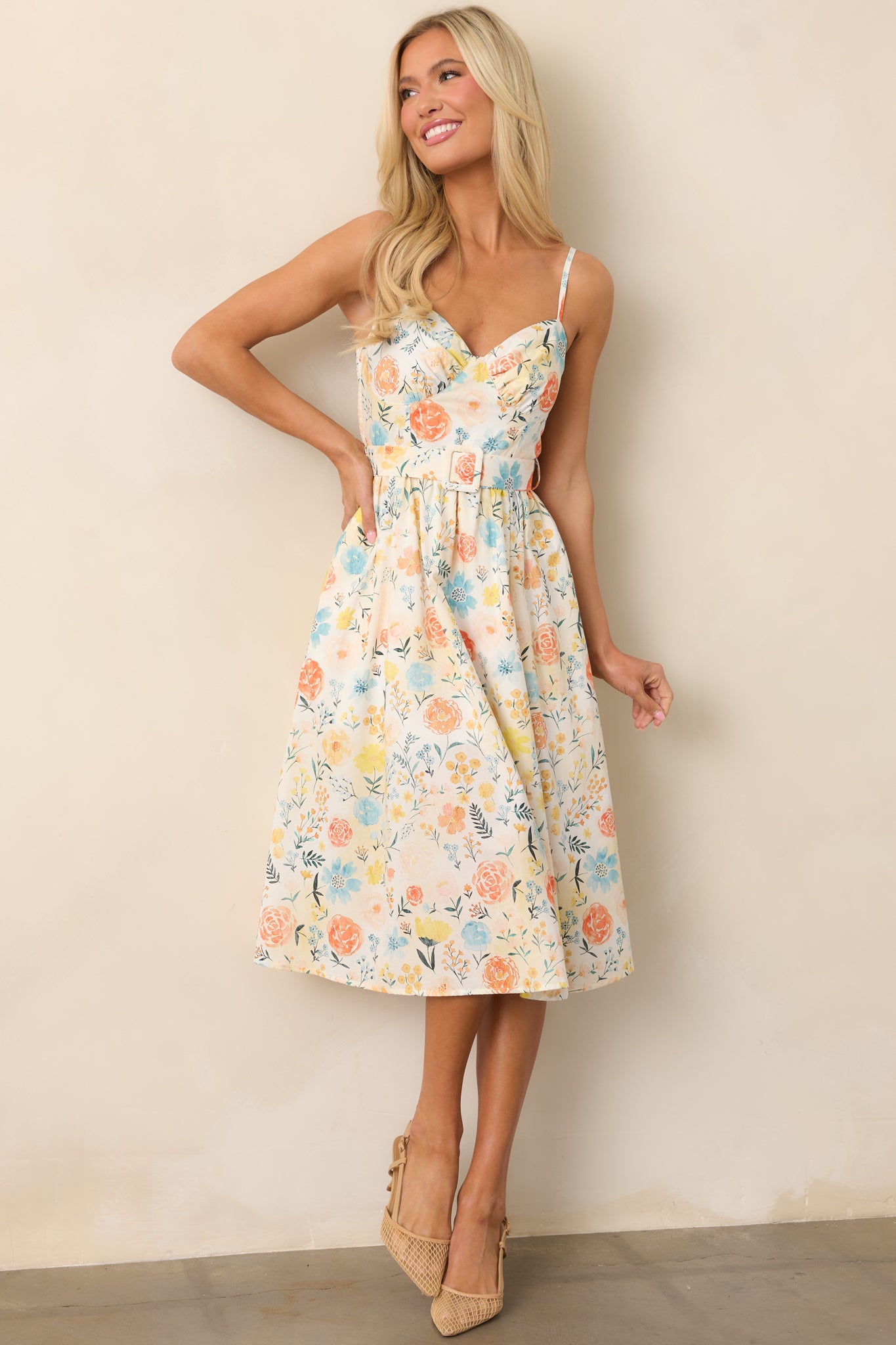 A full-length ivory dress with a multicolor floral print, adjustable straps, and a matching optional belt, offering a flattering silhouette.

