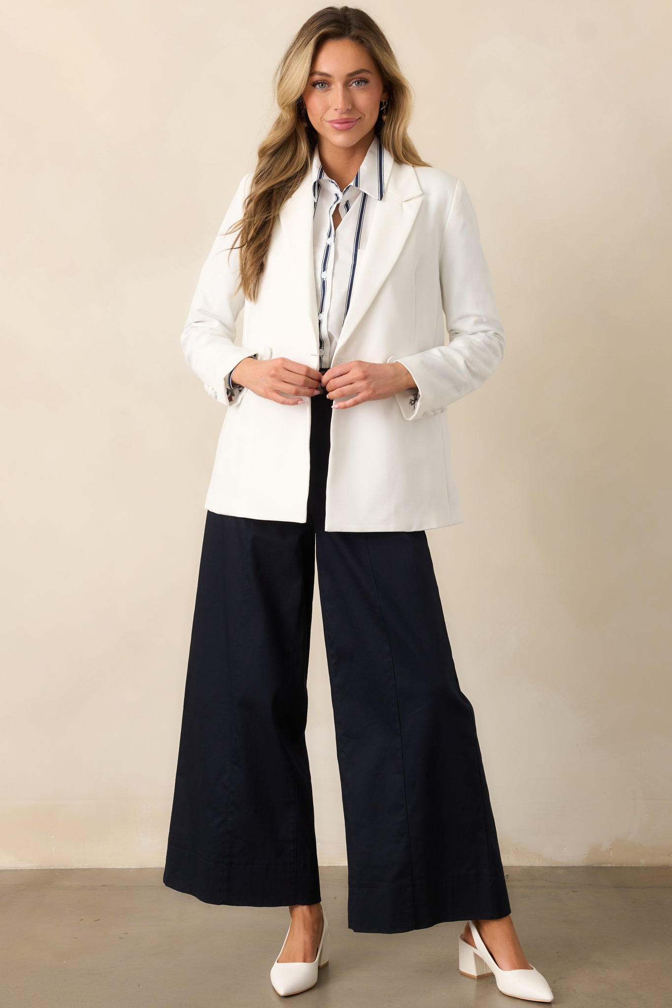 A full-length view of the white blazer showcasing its lapel collar, functional buttons, and structured fit.