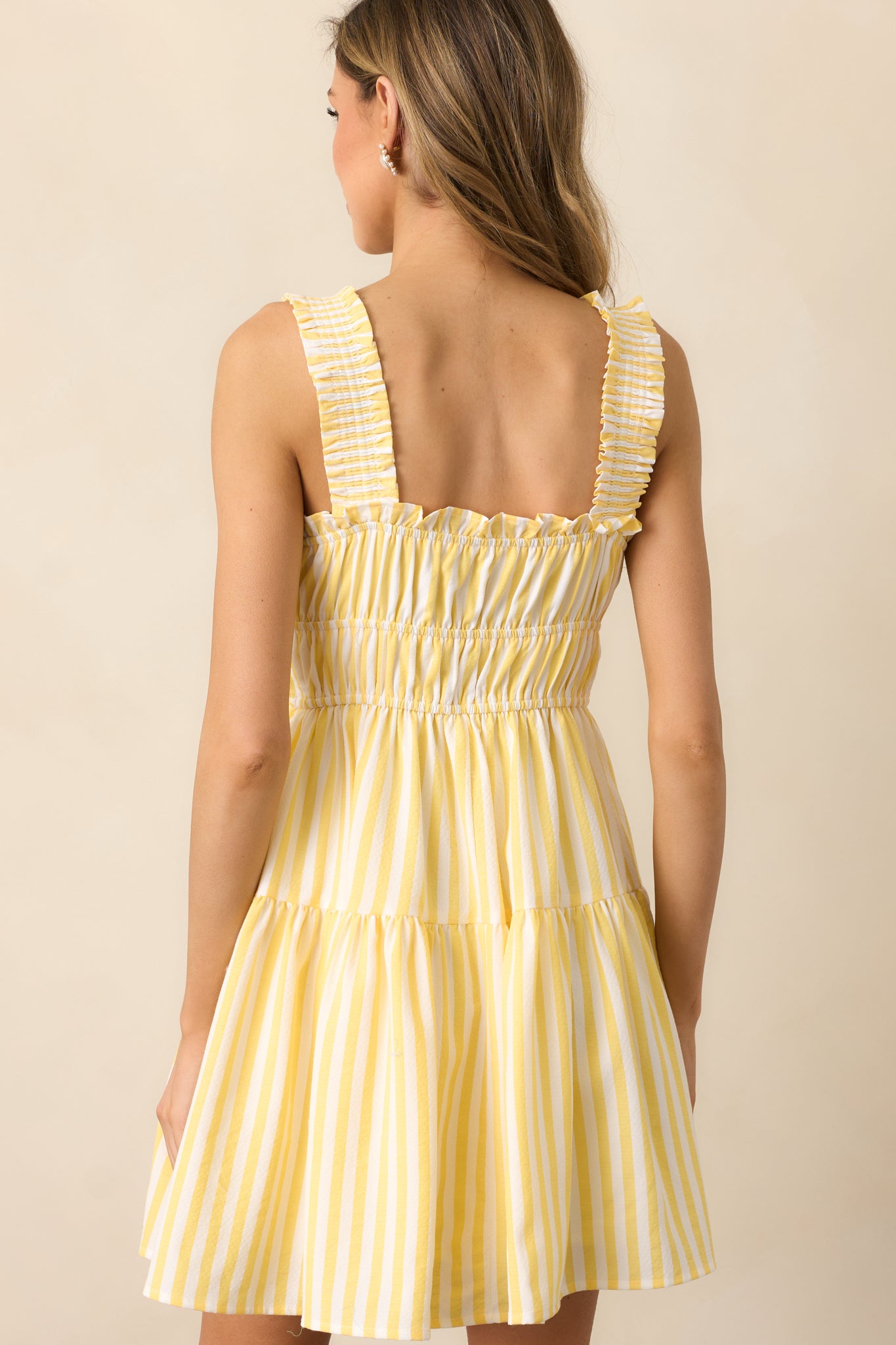 The yellow dress continues its flowy silhouette in the back, completing its sweet and feminine appeal.