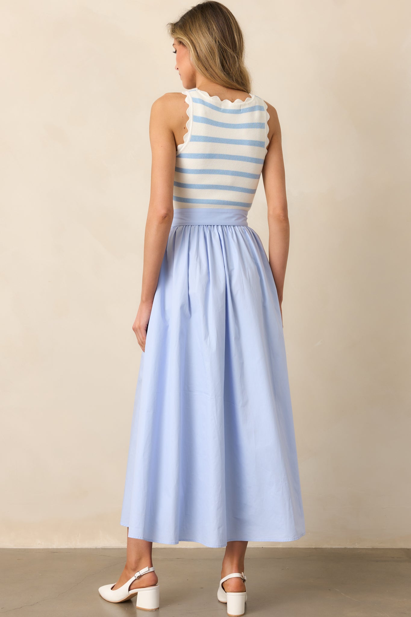 The blue midi dress continues its seamless blend of textures in the back, completing the polished look.